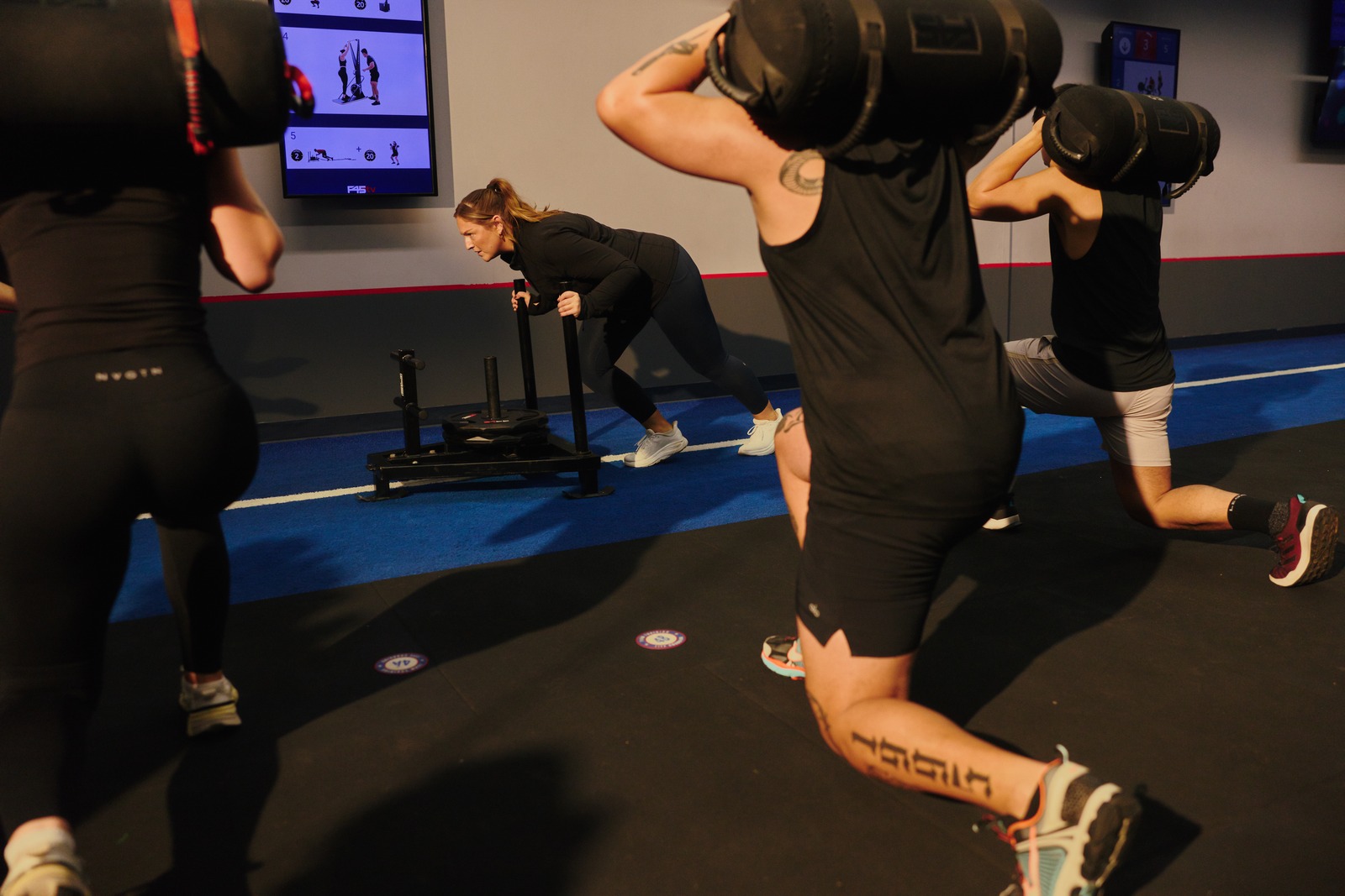 F45 members working through a sled push and sandbag lunges