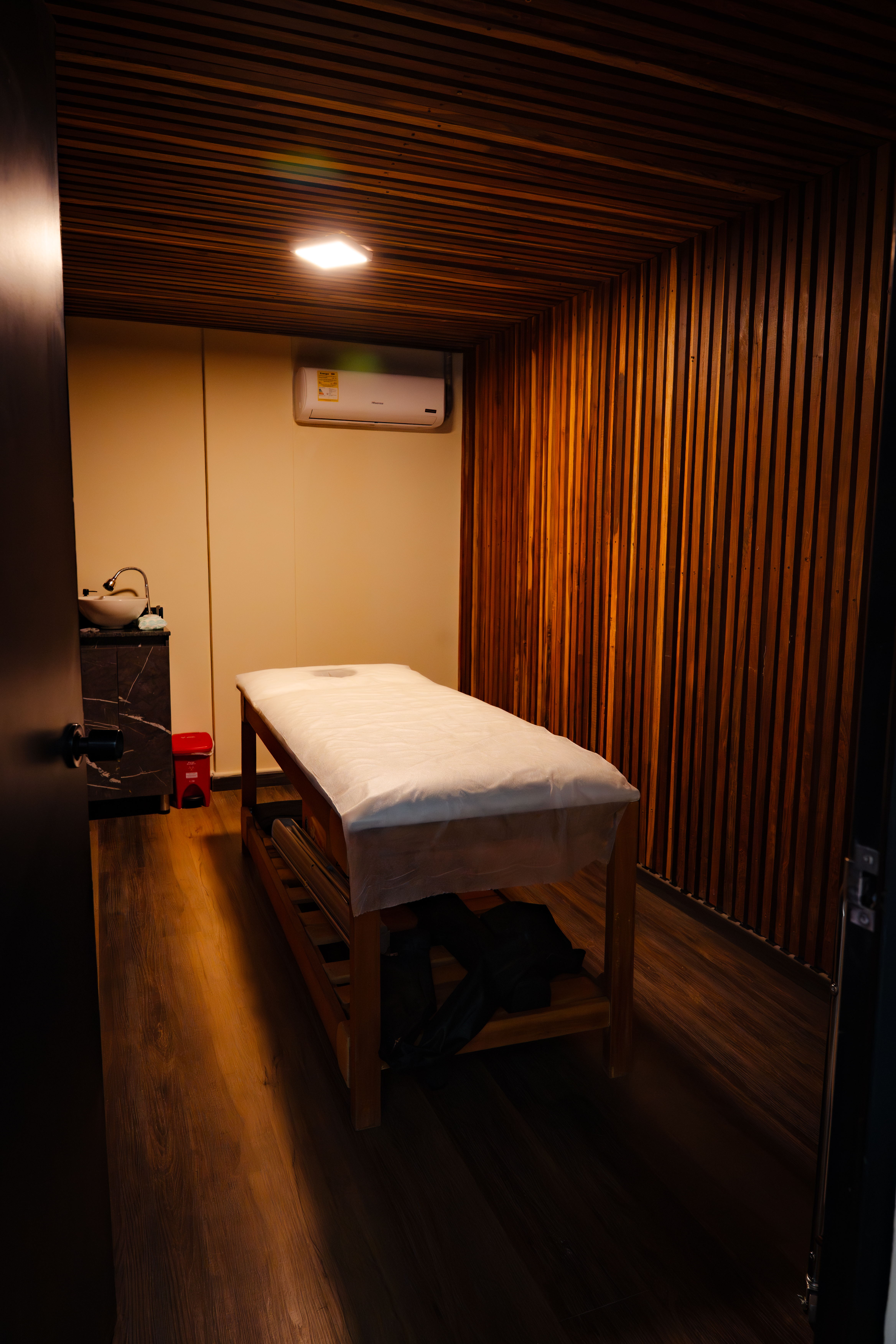 CIMA Spa private treatment room with warm wood-slat walls and softly lit massage table — El Poblado, Medellín