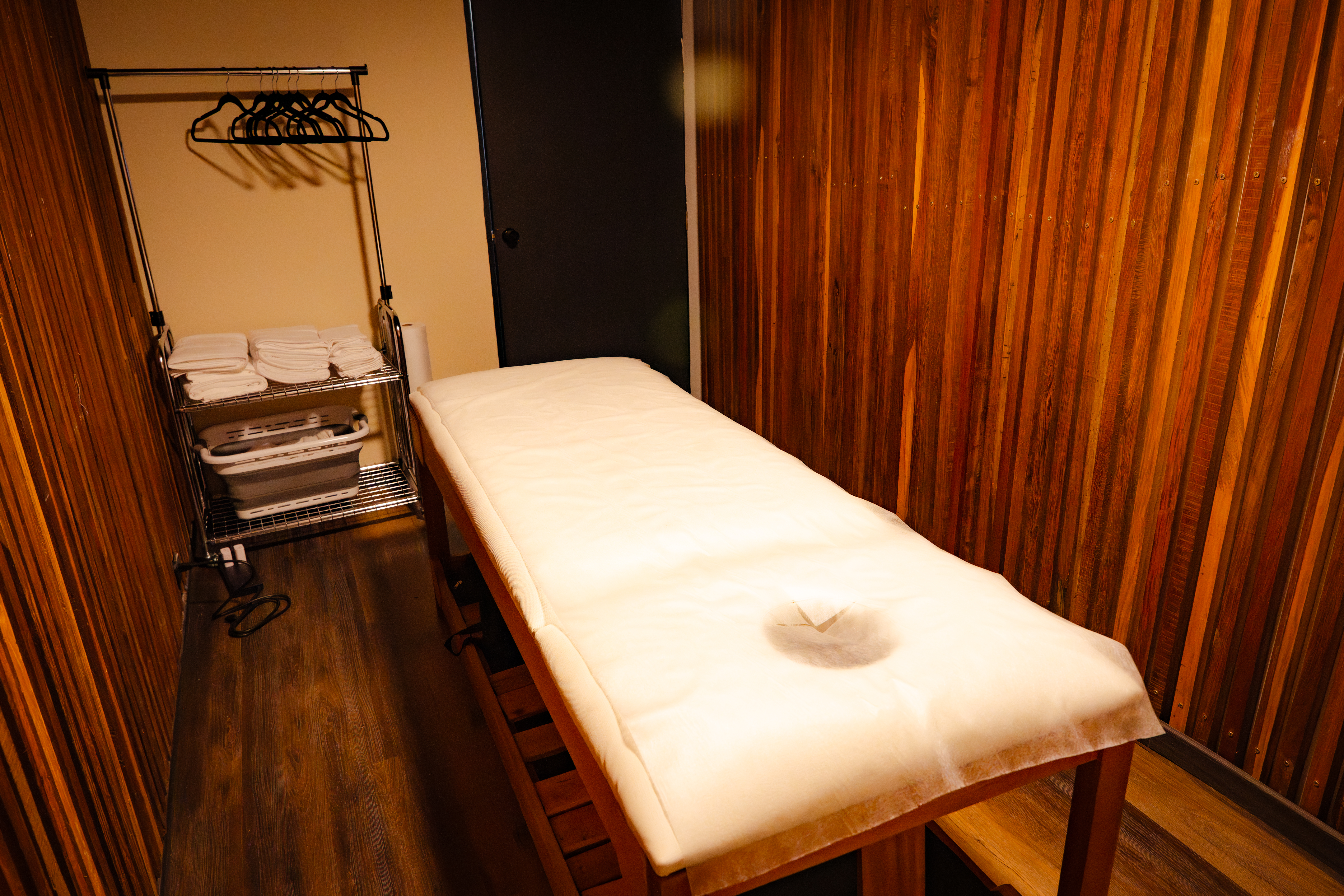 Private treatment room with warm wood-slat walls and a cushioned massage table at CIMA Spa