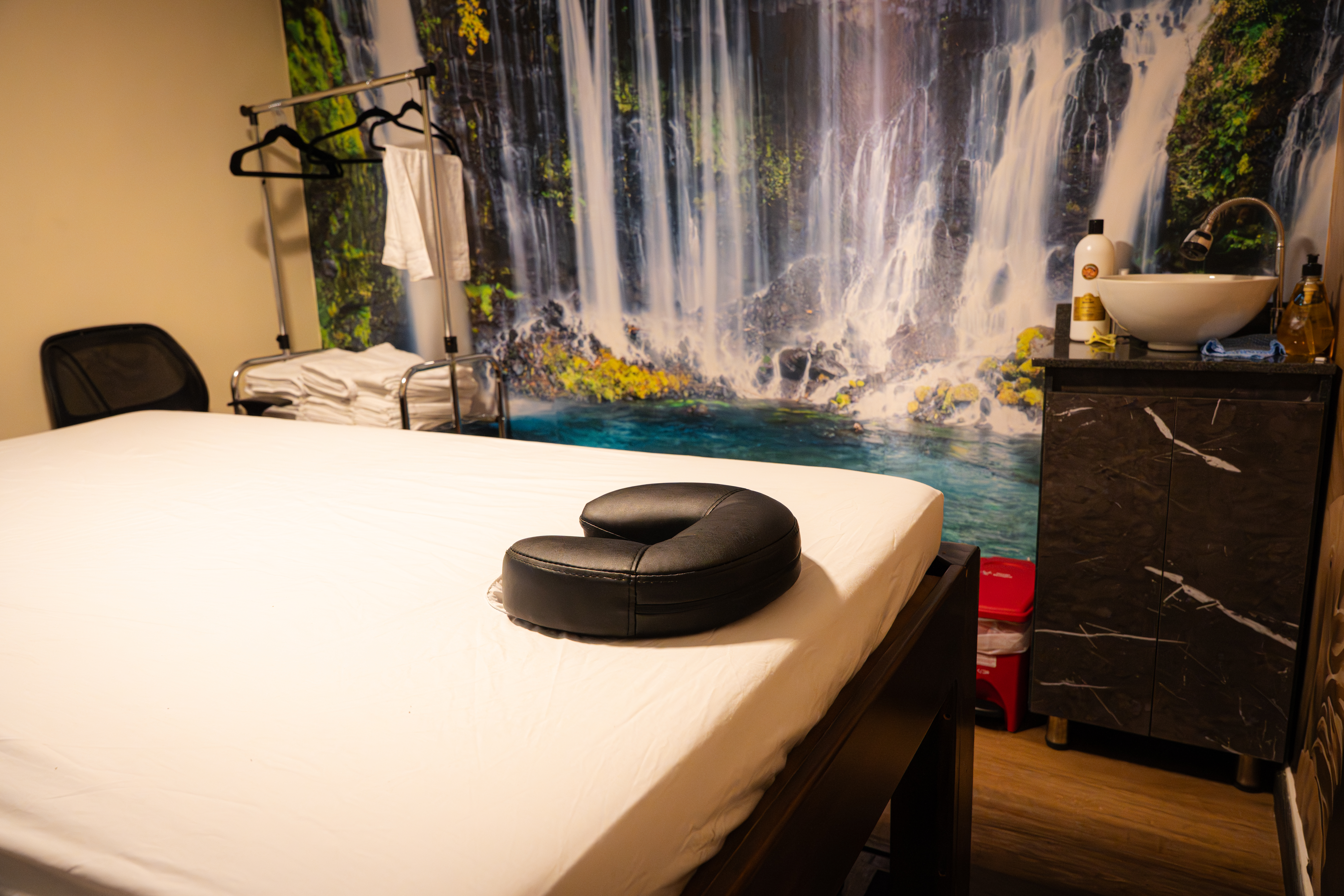 Treatment room with a serene waterfall mural backdrop and dressed massage table at CIMA Spa