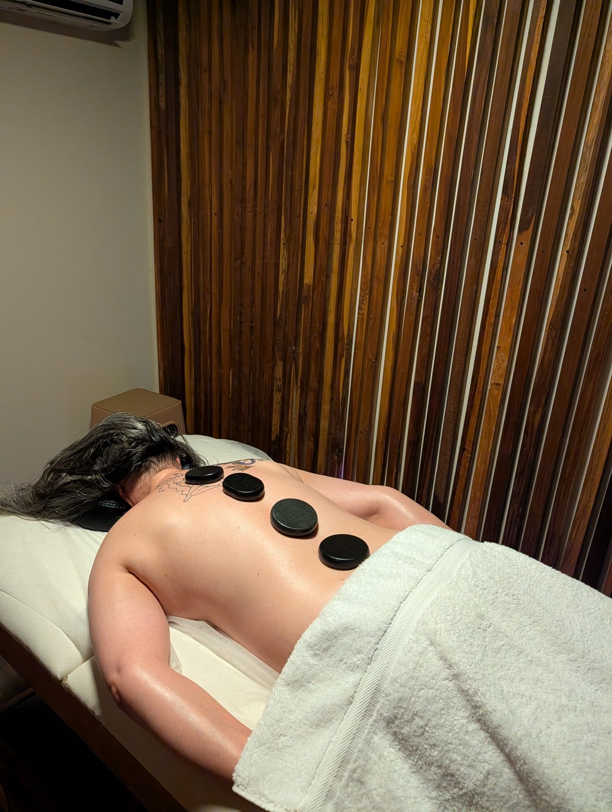 Hot stone therapy at CIMA Spa — warm basalt stones placed along the back during a massage, El Poblado