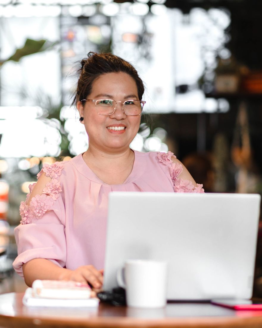 Jackie Cabrera smiling while working on her laptop at a cafe