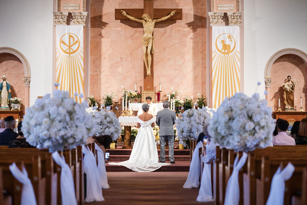 Church wedding ceremony with white floral aisle stands and wooden pews by MJ Event Designs