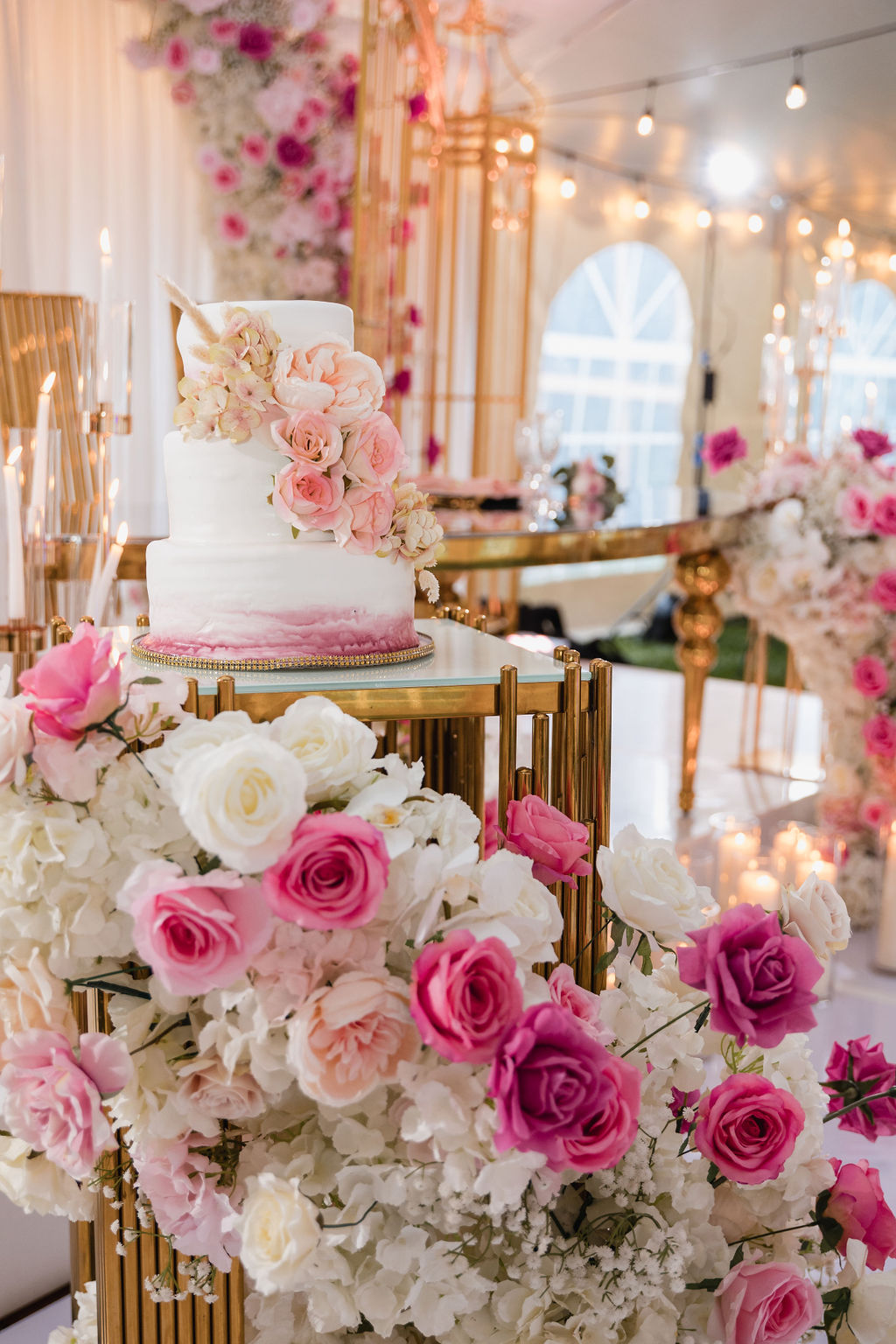 Ombré pink rose tiered cake with gold furniture and a floral backdrop by MJ Event Designs