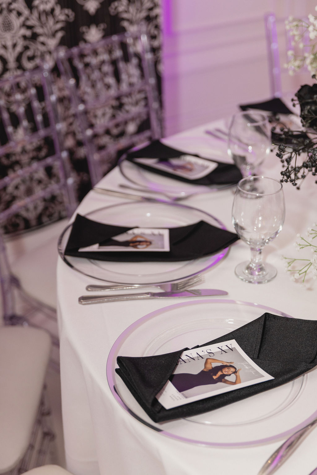Black and white XV with rose and baby's breath, ghost chairs and purple lighting by MJ Event Designs