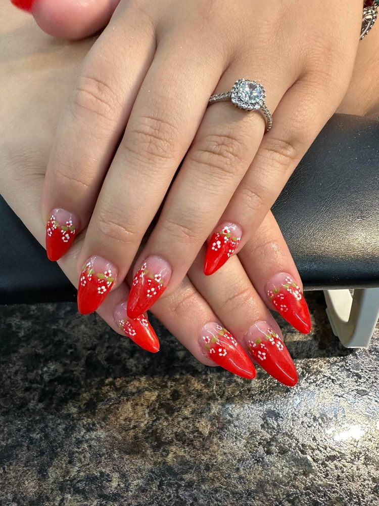 Almond nails with red tips and tiny hand-painted white flowers