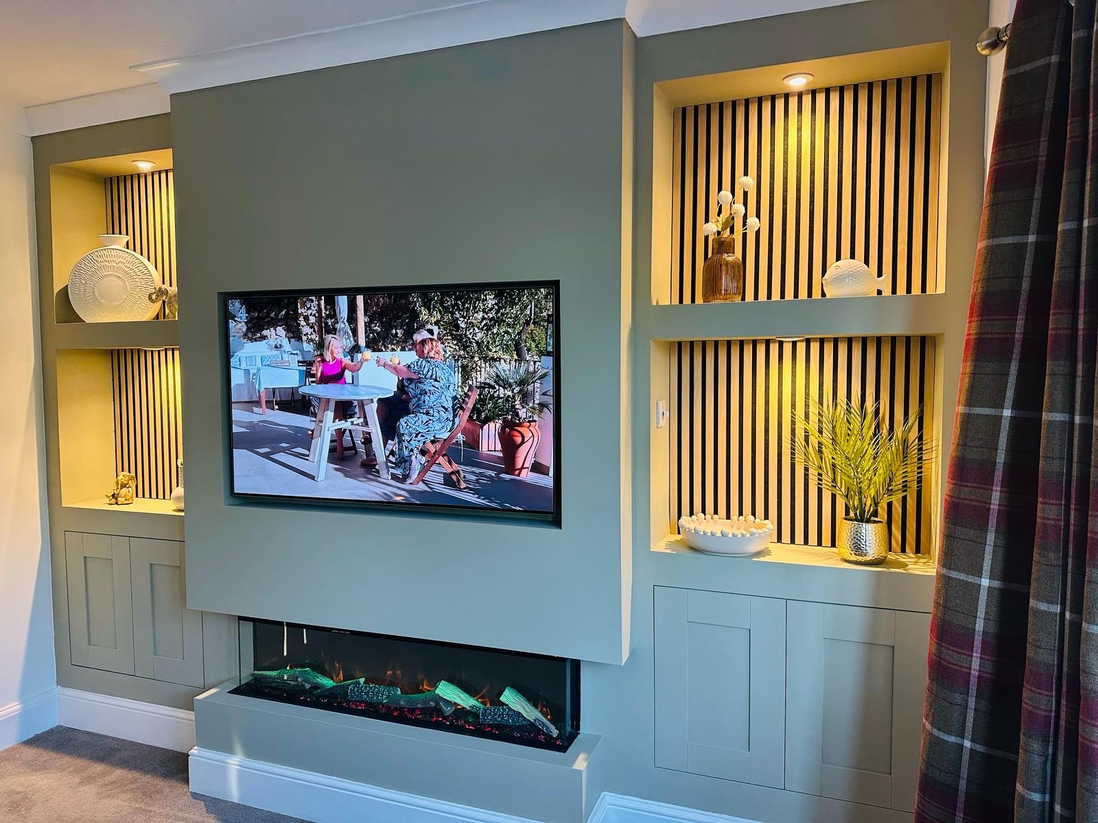 Bespoke sage-green media wall with built-in alcoves and electric fireplace by The Media Wall Co.