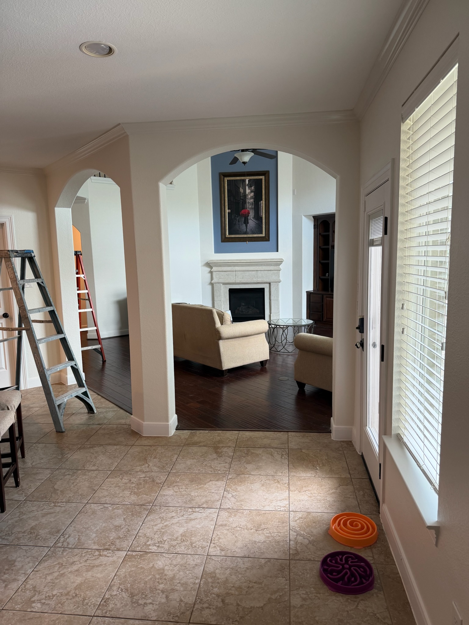 Professional painter sanding a drywall patch with a block in a bright, dust-free living room.