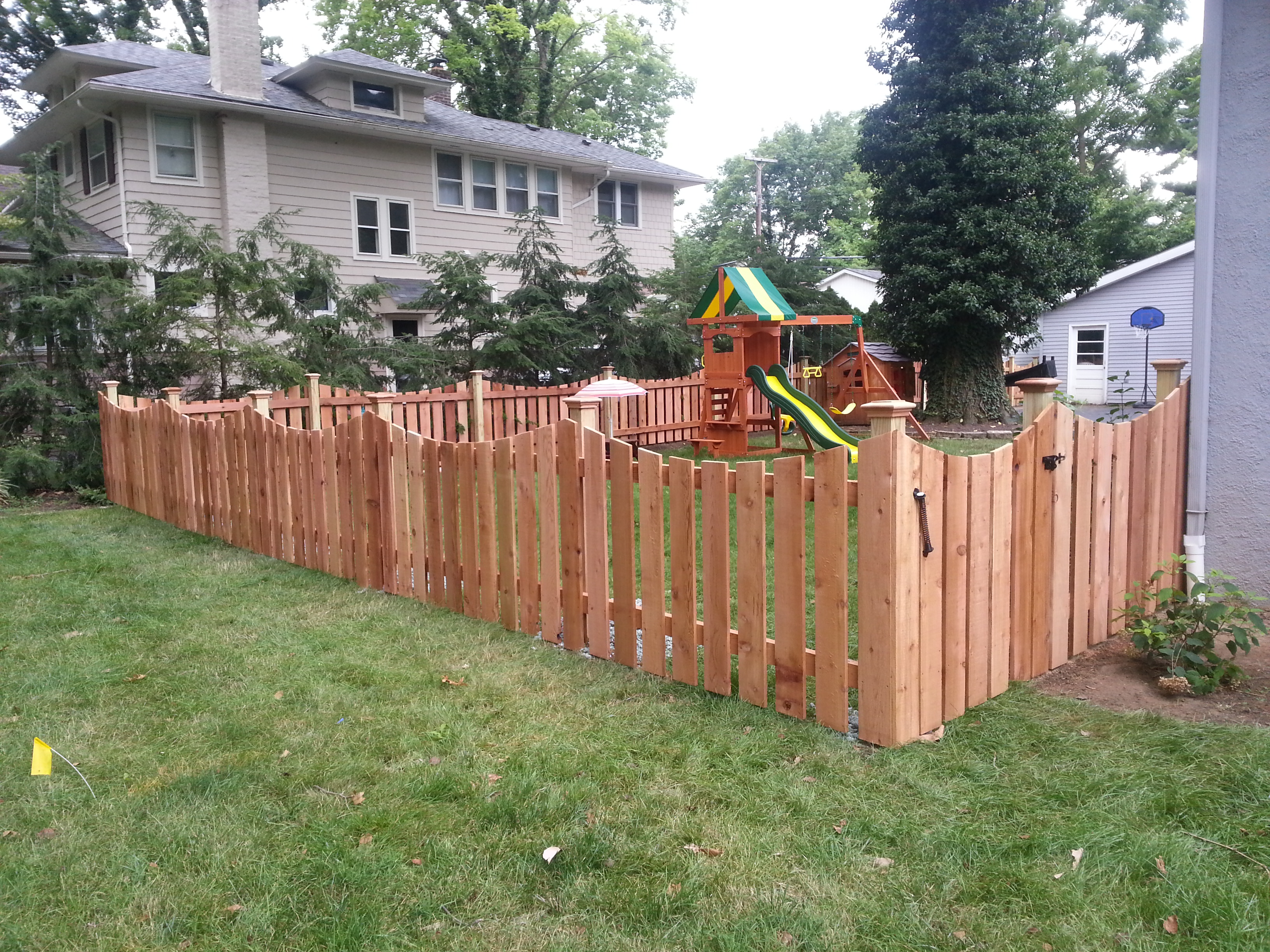 Scalloped wood picket safety fence enclosing a backyard children's playground in Upper Arlington, OH.