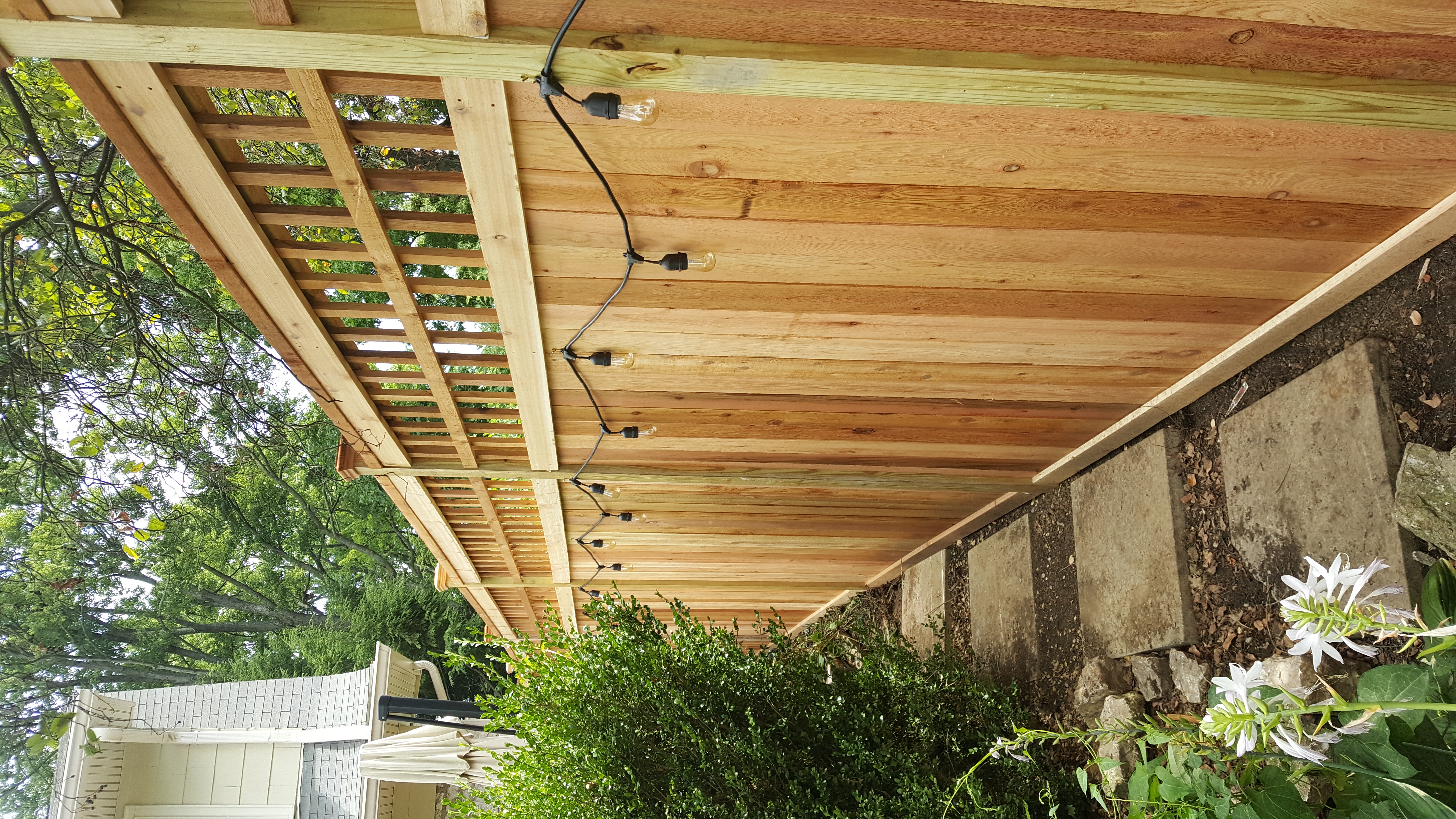 Custom wood privacy fence with warm outdoor string lights and lattice top in Delaware, OH.