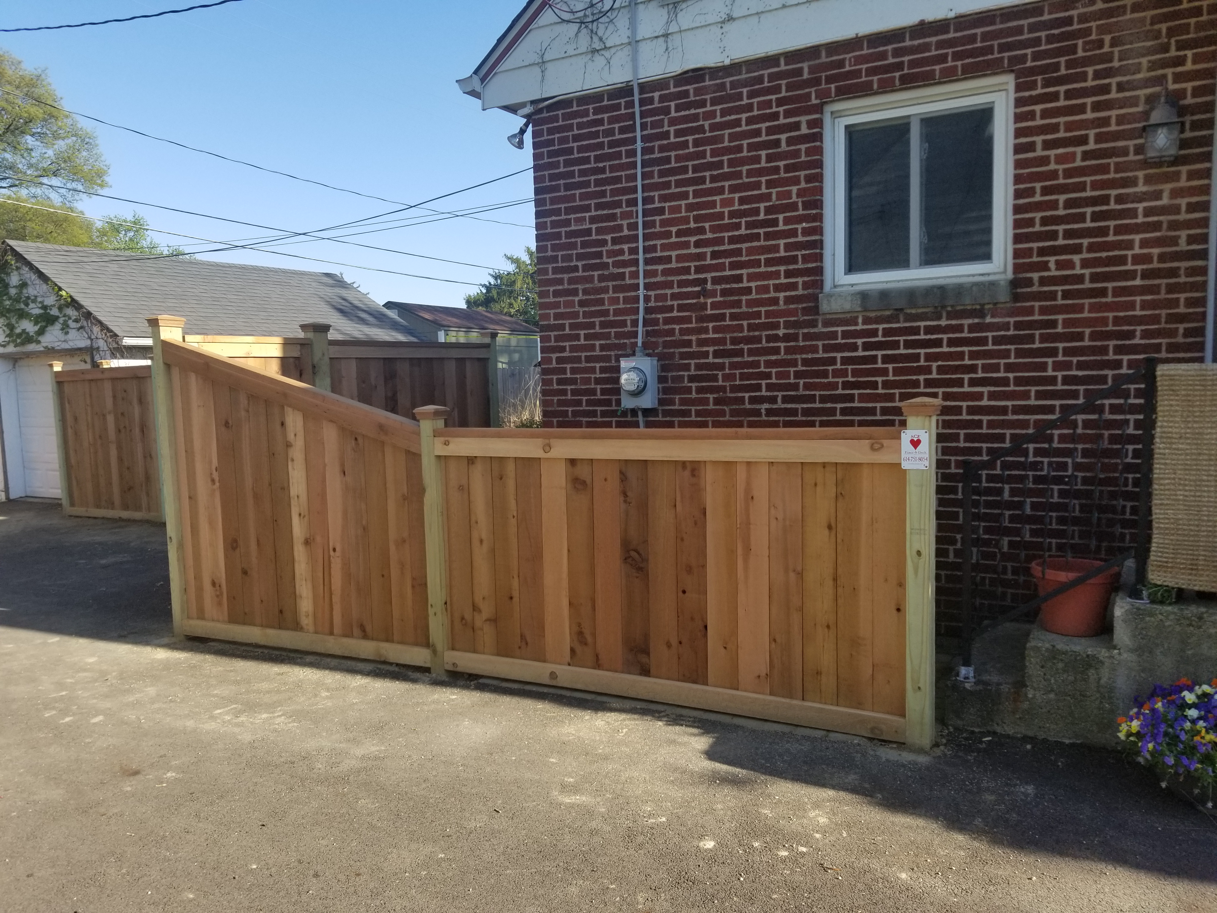 Custom stepped wood privacy fence adapting to a sloped concrete driveway in Hilliard, OH.