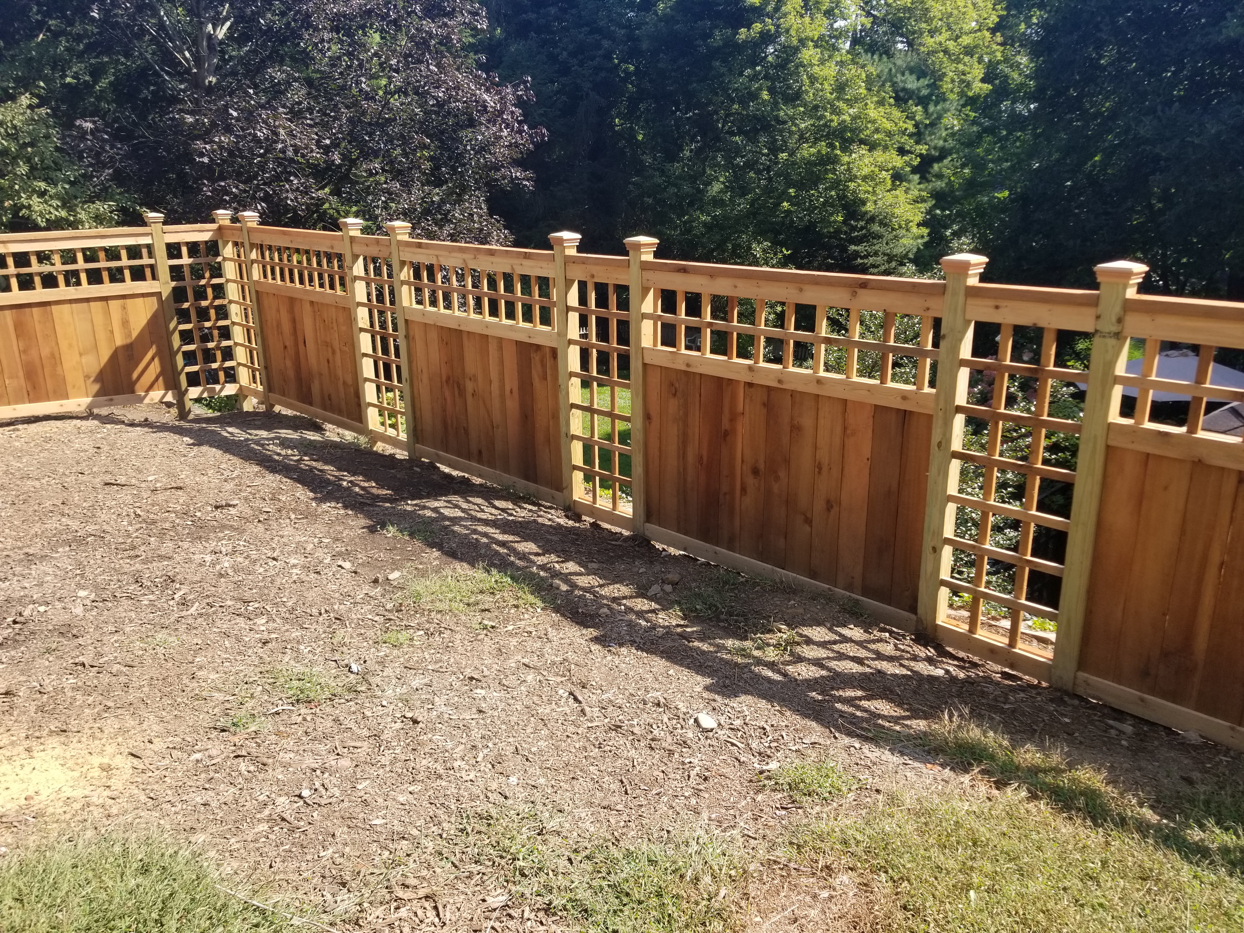 Custom treated wood fence with integrated ornamental lattice panels in Pataskala, OH.