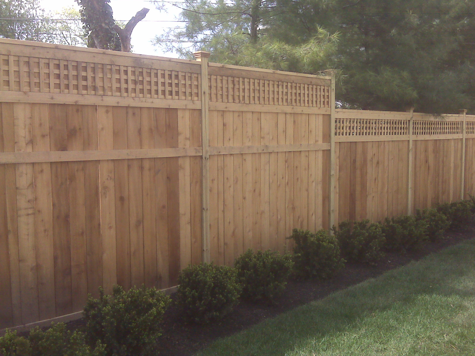 Custom wood privacy fence with square lattice top and decorative post caps in Lancaster, OH.