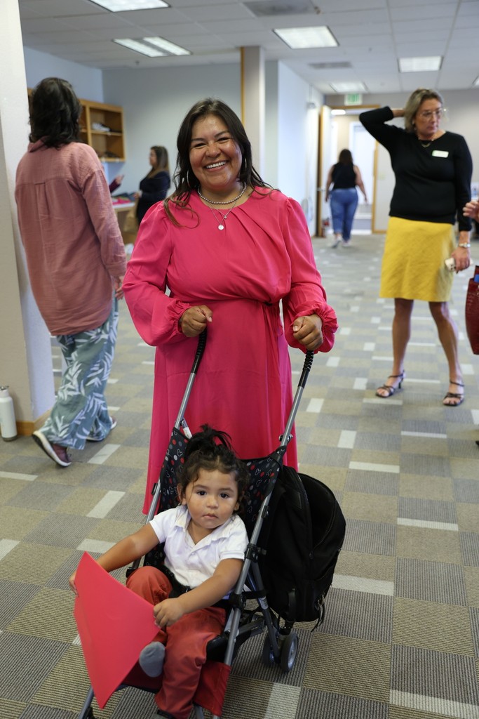 A smiling Best Foot Forward participant in a pink dress with her young child