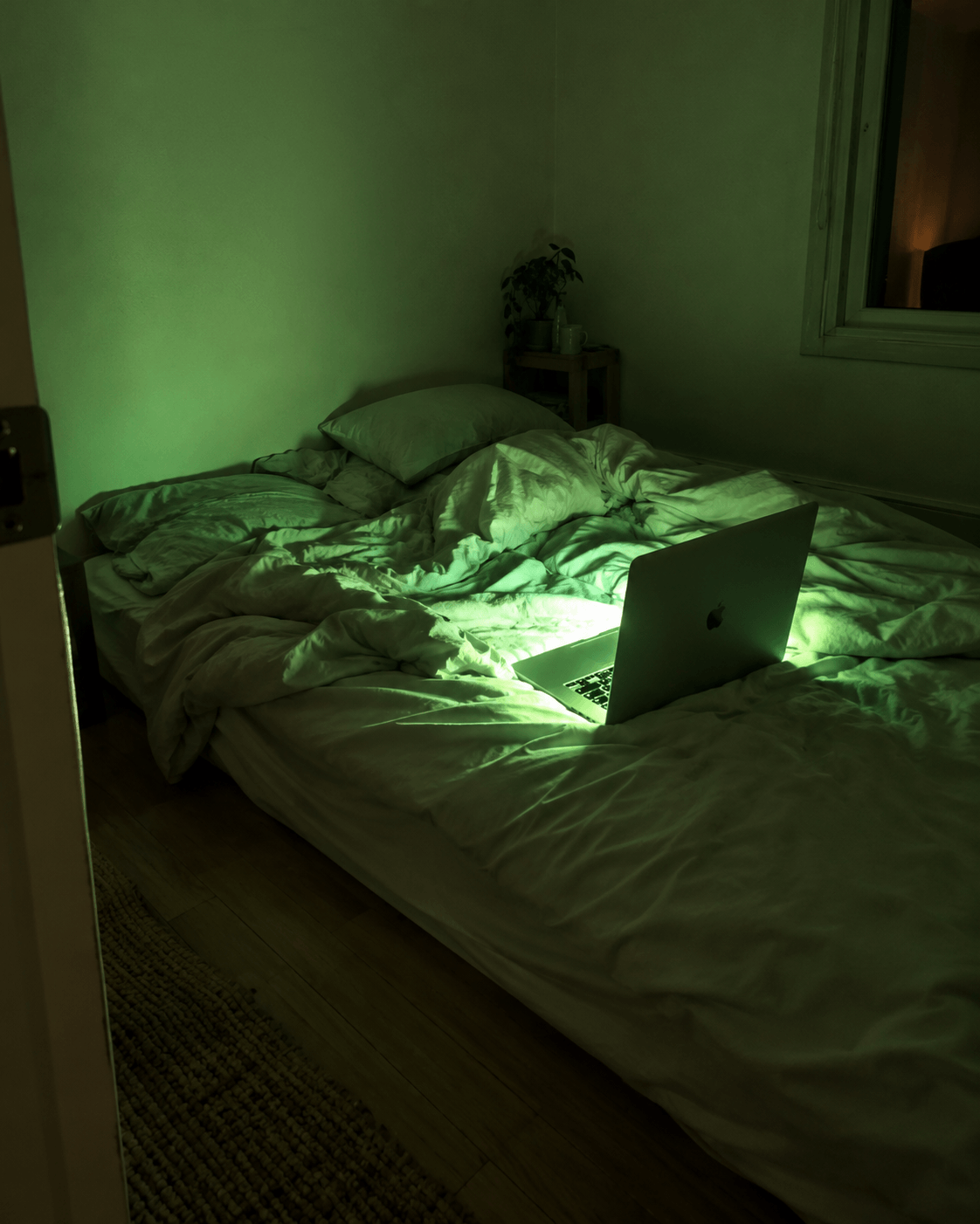 A mattress on the floor of a bare room, a laptop open beside it