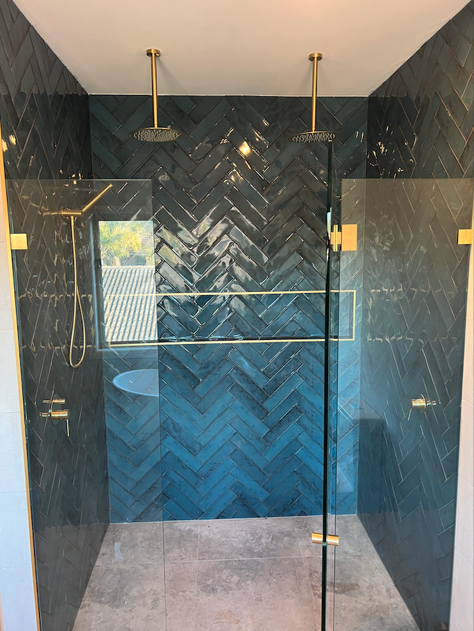 Blue herringbone feature shower with gold fixtures — Woonona bathroom renovation