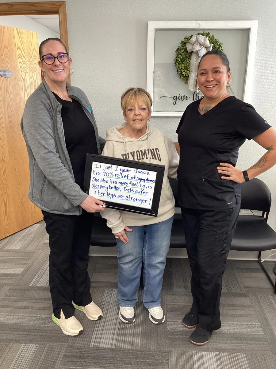 Patient Jackie holding a whiteboard about her neuropathy progress with Althoff Wellness Clinic team members