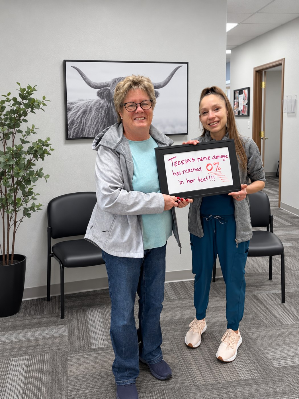 Patient Teresa holding a whiteboard about her neuropathy progress with an Althoff Wellness Clinic team member in Cheyenne