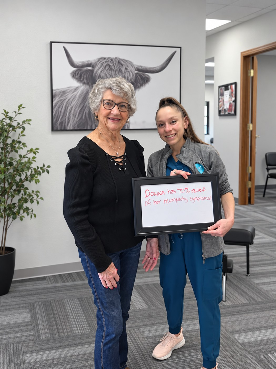 Patient Donna holding a whiteboard about her neuropathy progress with an Althoff Wellness Clinic team member in Cheyenne