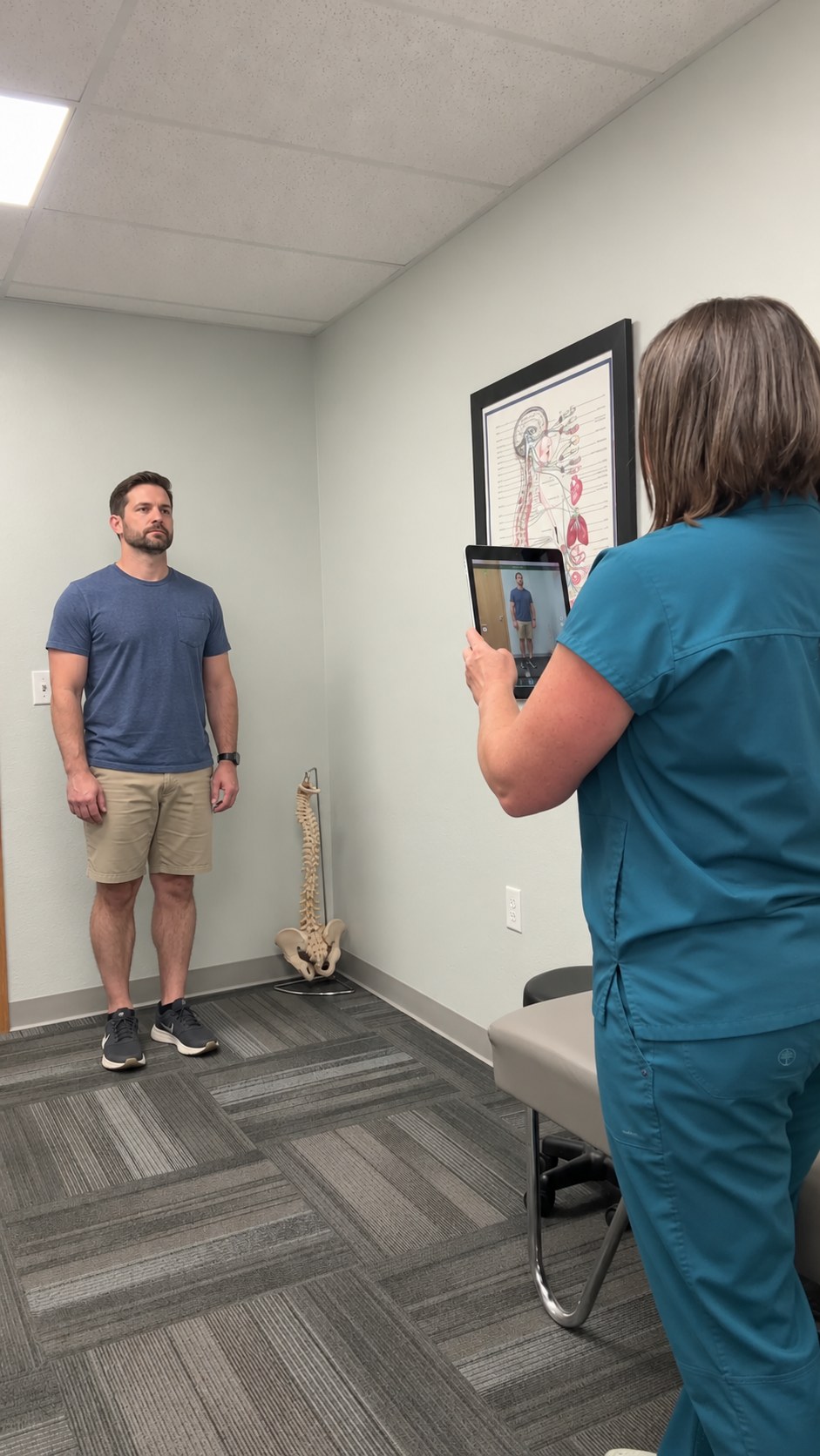 A team member taking a digital posture scan of a male patient on a tablet during a spine evaluation in Cheyenne, WY