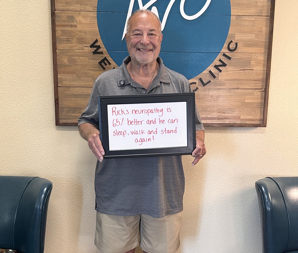 Rick, a neuropathy patient, holding a whiteboard about his progress at Althoff Wellness Clinic