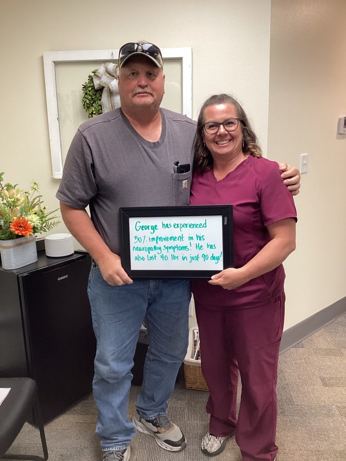 Patient George holding a whiteboard about his neuropathy progress with an Althoff Wellness Clinic team member