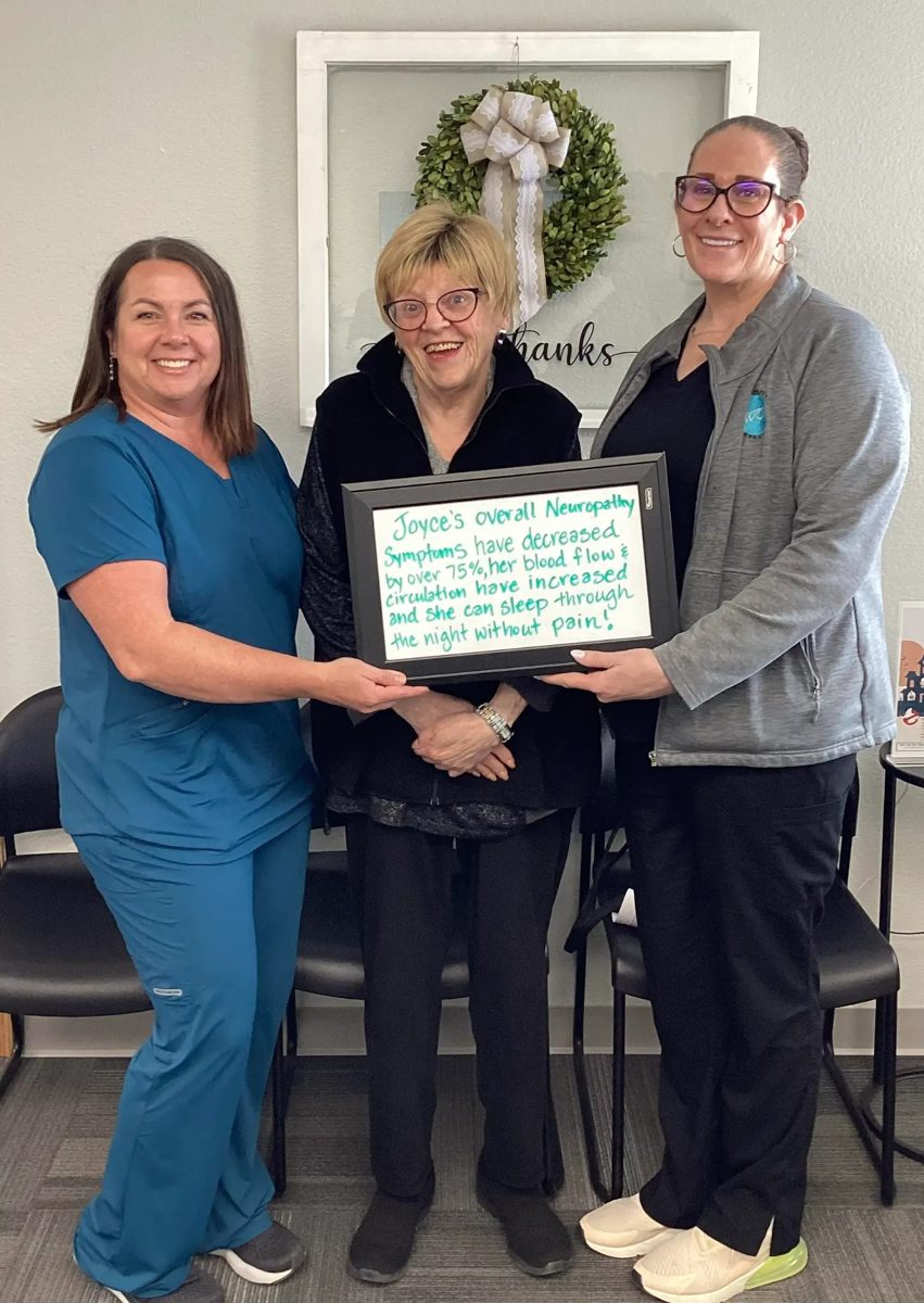 Patient Joyce holding a whiteboard about her neuropathy progress with Althoff Wellness Clinic team members