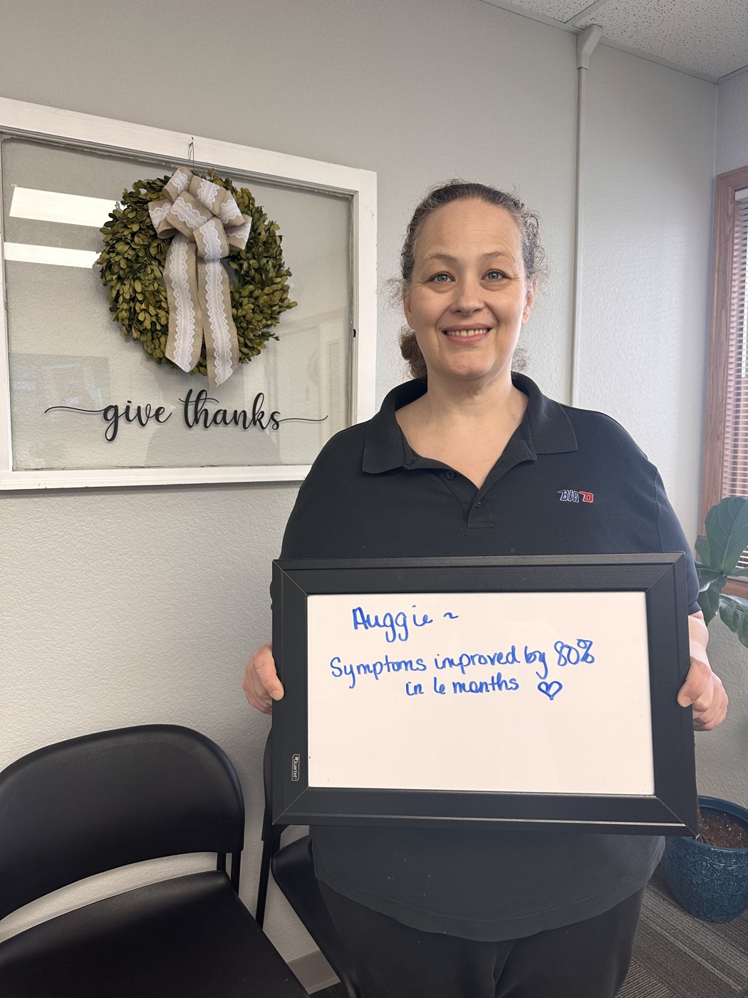 Auggie, a neuropathy patient at Althoff Wellness Clinic, holding a whiteboard about her progress