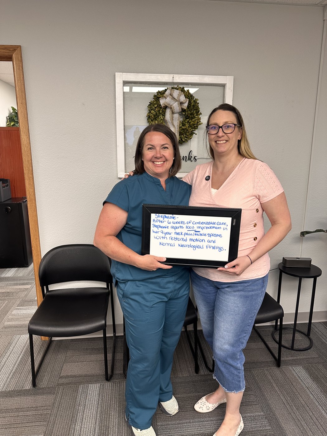Stephanie holding a whiteboard about her neck pain progress at Althoff Wellness Clinic in Cheyenne