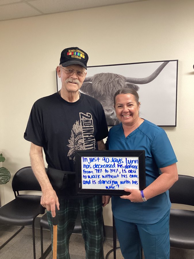 Patient Lynn holding a whiteboard about his neuropathy progress with an Althoff Wellness Clinic team member