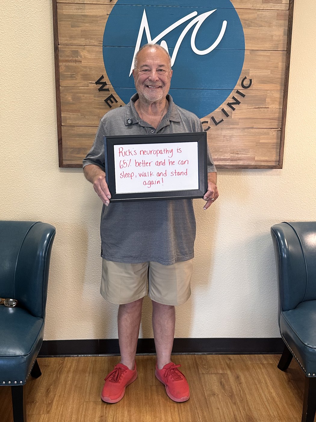 Rick, a neuropathy patient, holding a whiteboard about his progress at Althoff Wellness Clinic