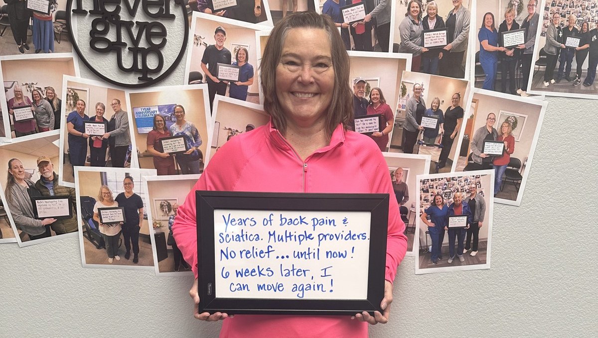 Linda holding a whiteboard about her back pain and sciatica progress at Althoff Wellness Clinic in Cheyenne