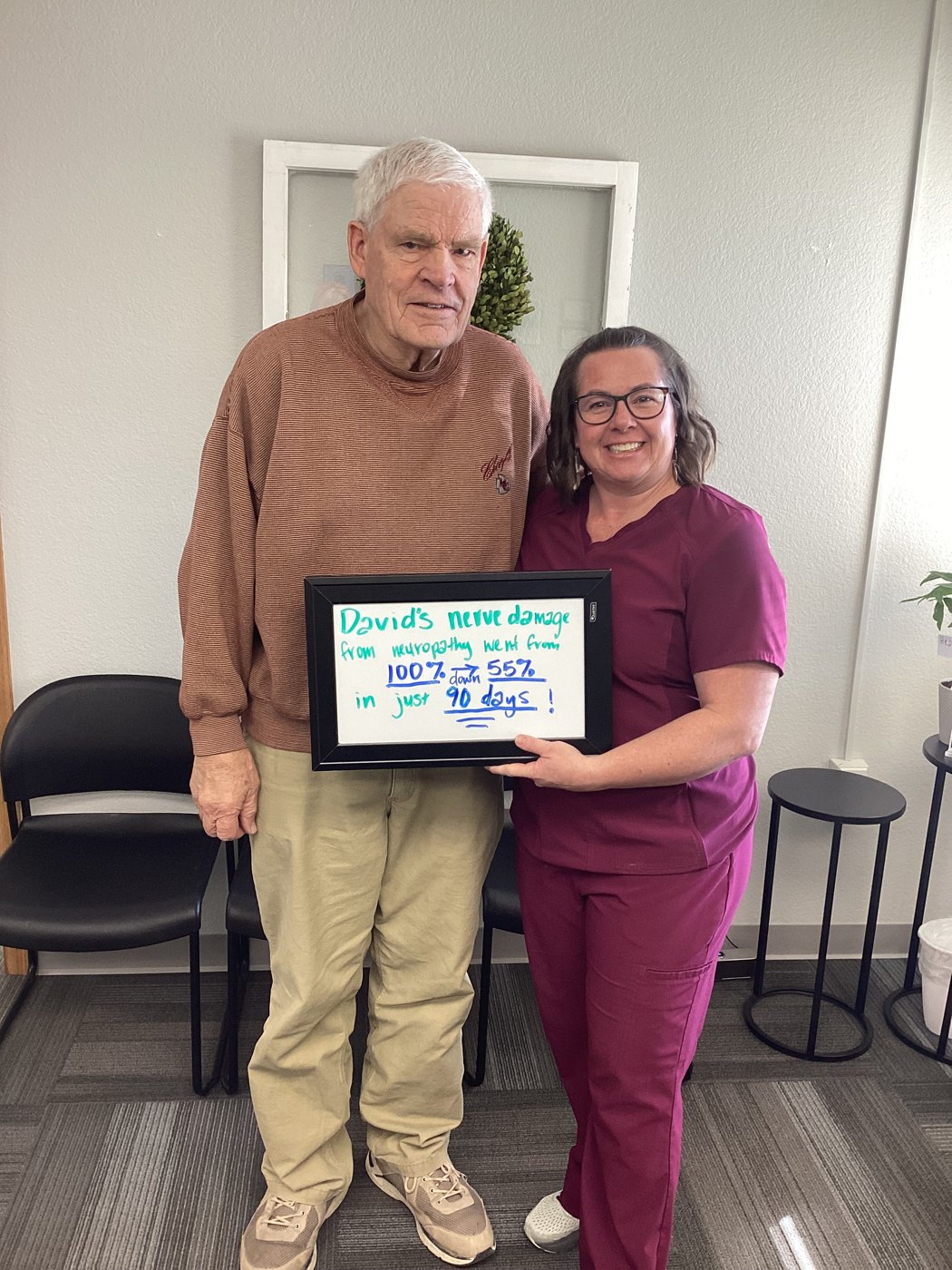 Patient David holding a whiteboard about his neuropathy progress with Althoff Wellness Clinic team members in Cheyenne