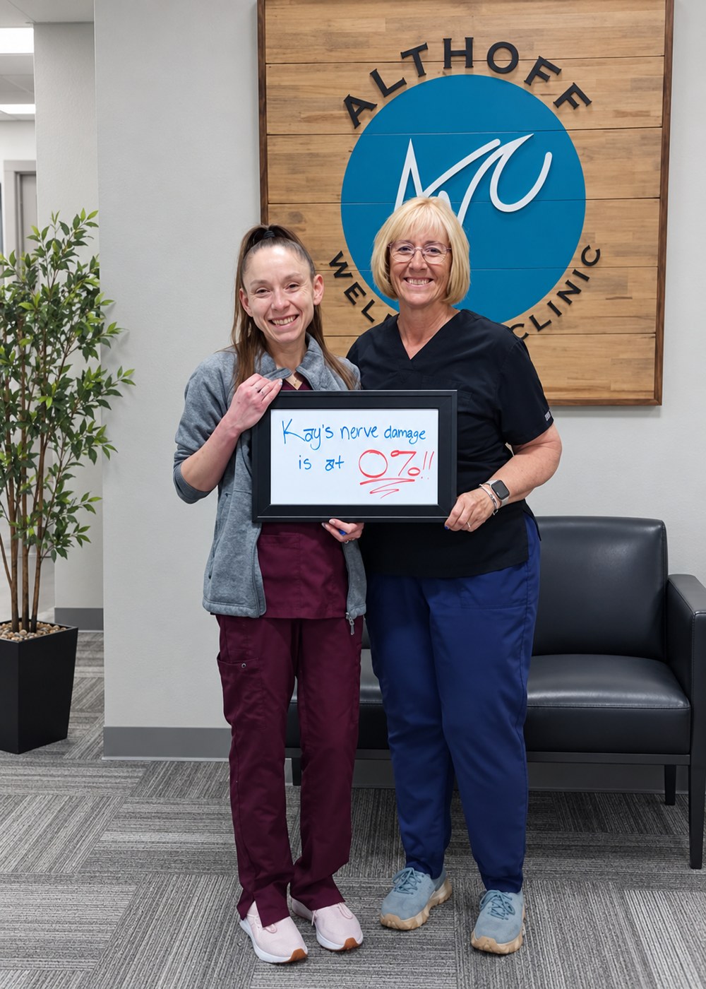 Patient Kay holding a whiteboard about her neuropathy progress with an Althoff Wellness Clinic team member in Cheyenne