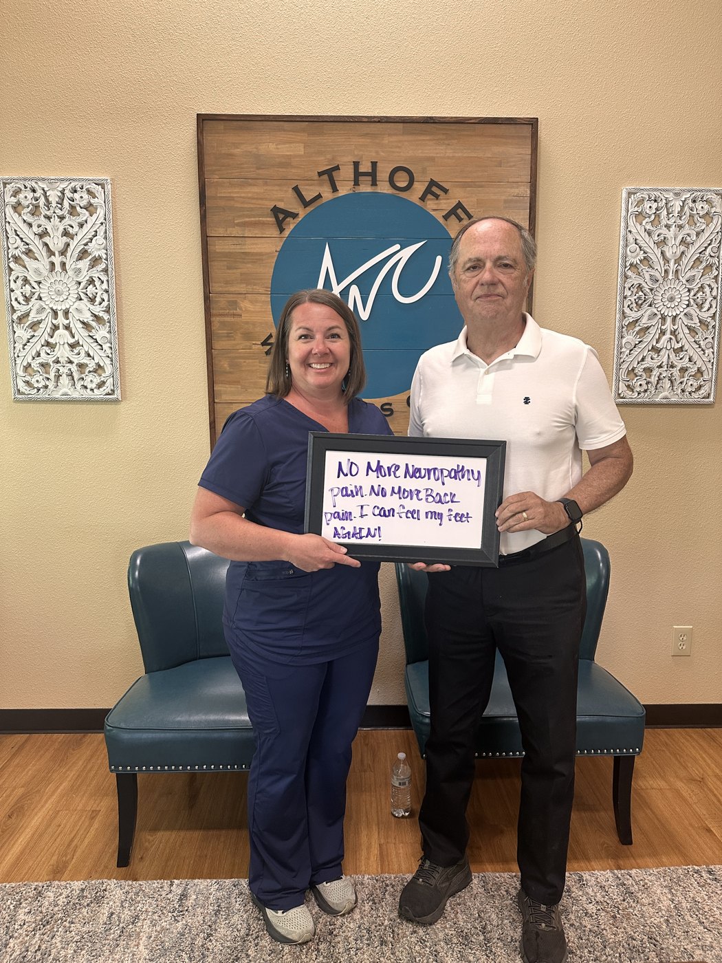 Patient Tony holding a whiteboard about his neuropathy and back pain progress with Althoff Wellness Clinic team members in Cheyenne