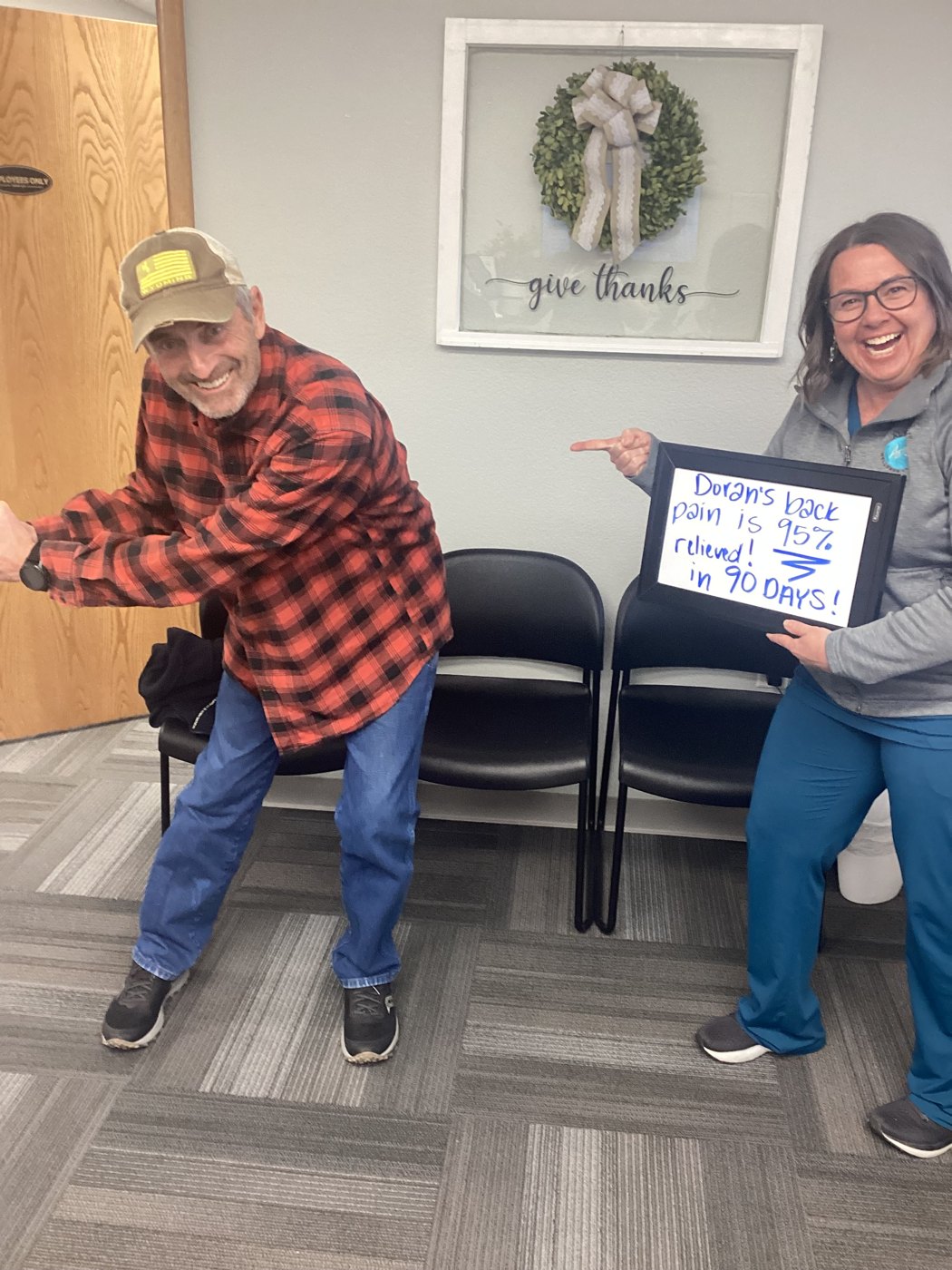 Patient Doran celebrating his back pain progress with an Althoff Wellness Clinic team member holding a whiteboard