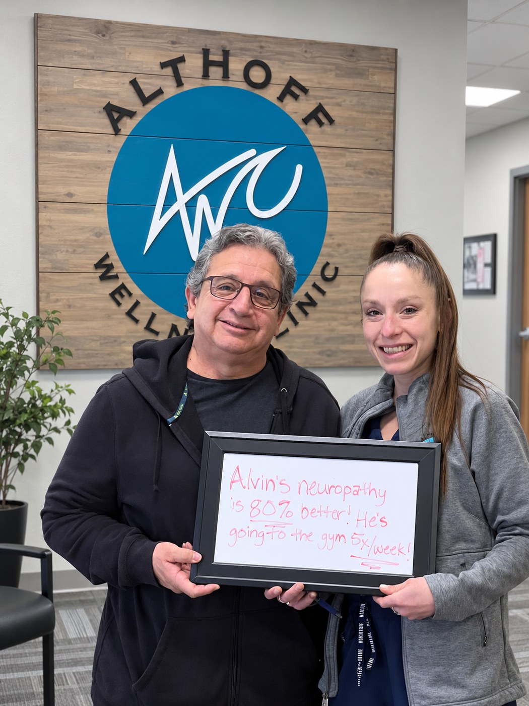 Patient Alvin holding a whiteboard about his neuropathy progress with an Althoff Wellness Clinic team member in Cheyenne