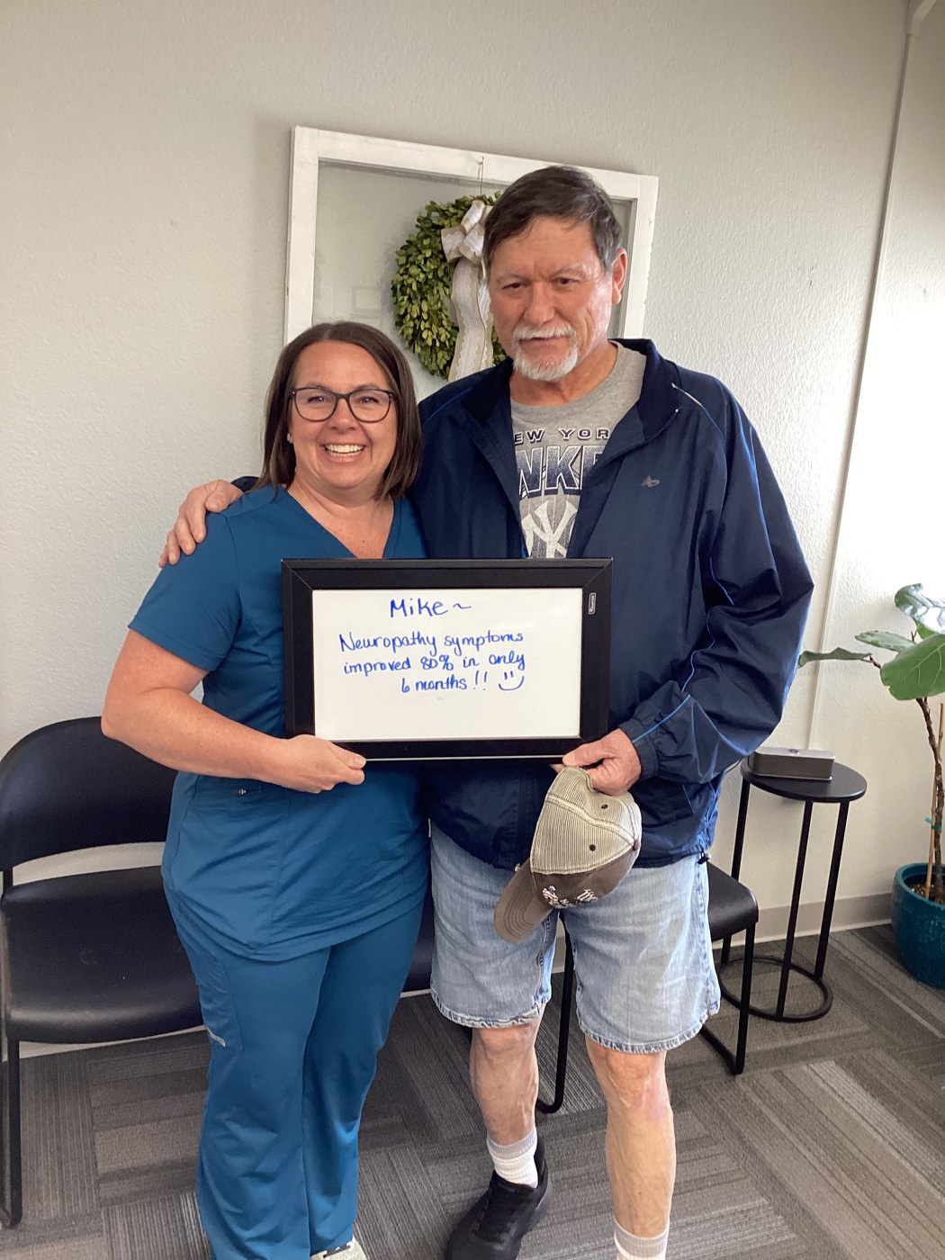 Patient Mike holding a whiteboard about his neuropathy progress with Althoff Wellness Clinic team members in Cheyenne