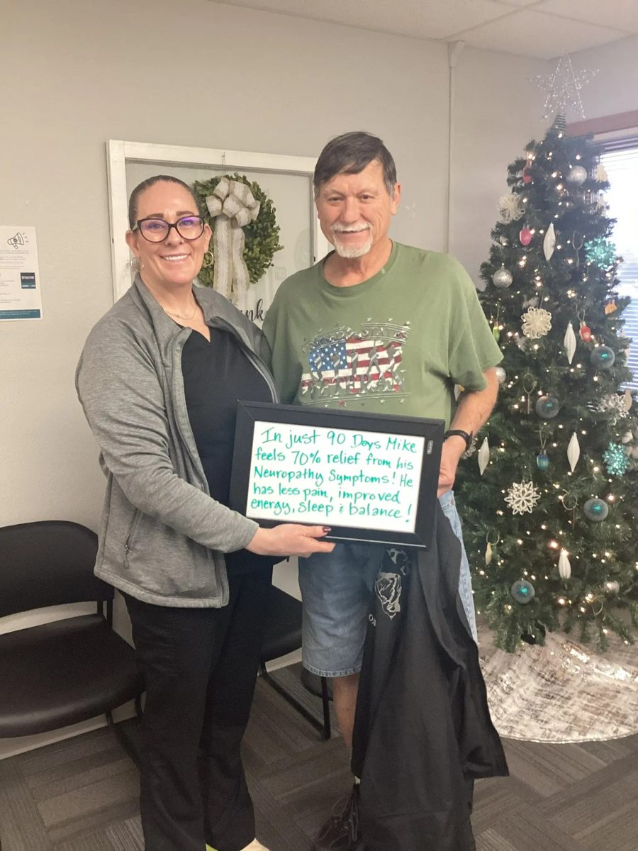 Patient Mike holding a whiteboard about his neuropathy progress with an Althoff Wellness Clinic team member