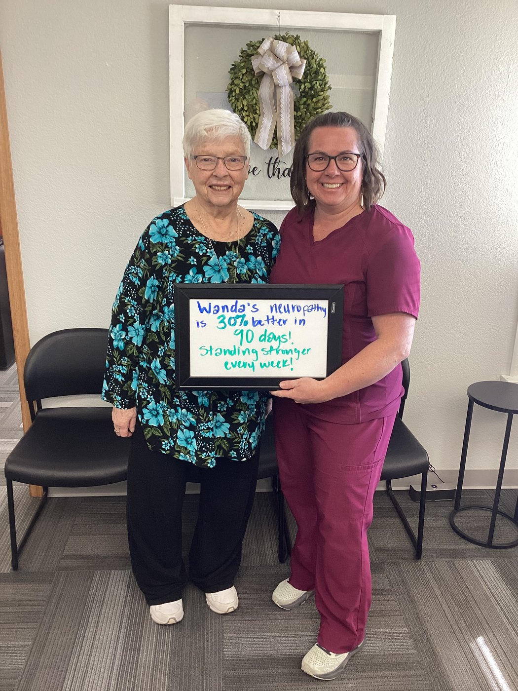 Patient Wanda holding a whiteboard about her neuropathy progress with Althoff Wellness Clinic team members in Cheyenne