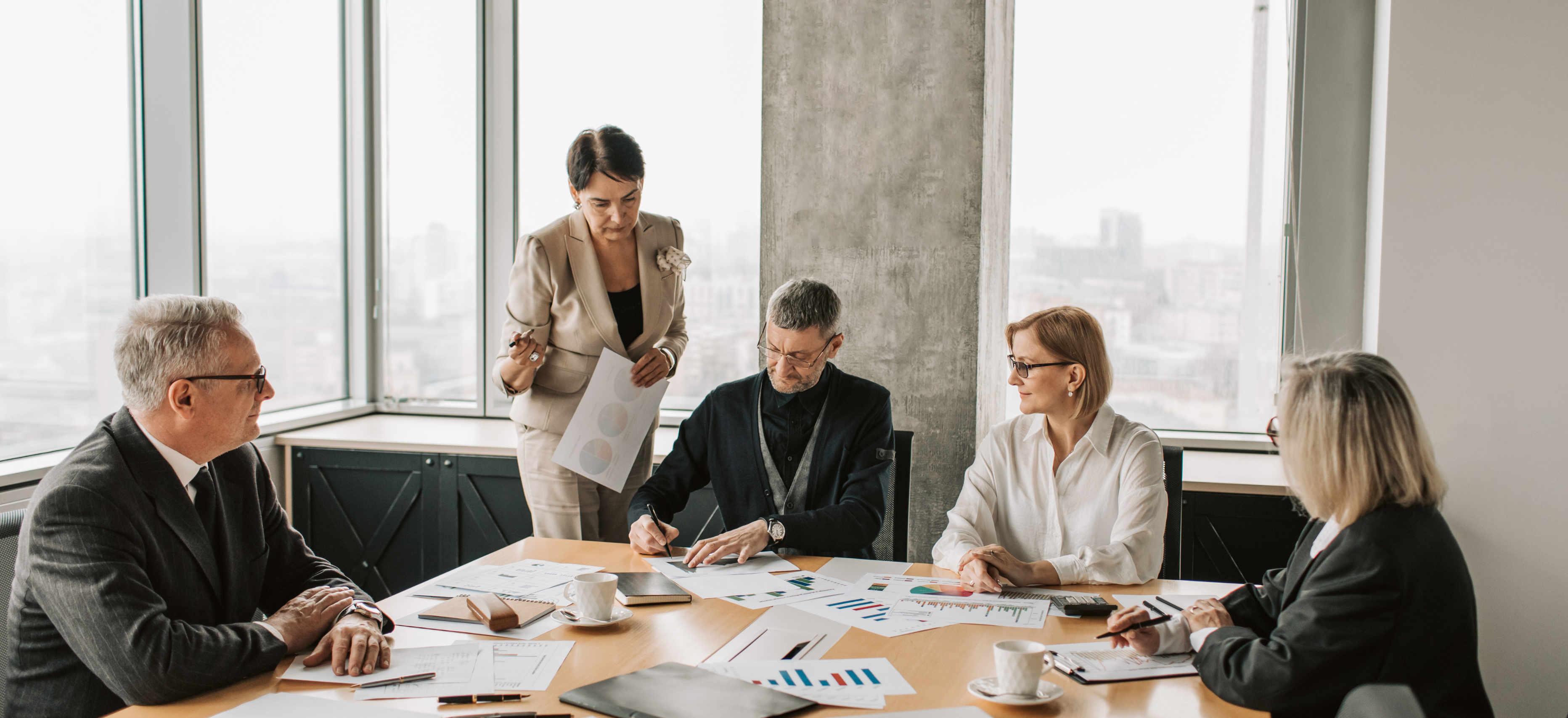 Law firm leadership team reviewing financial reports and charts in a conference room, planning profitability and tax strategy.