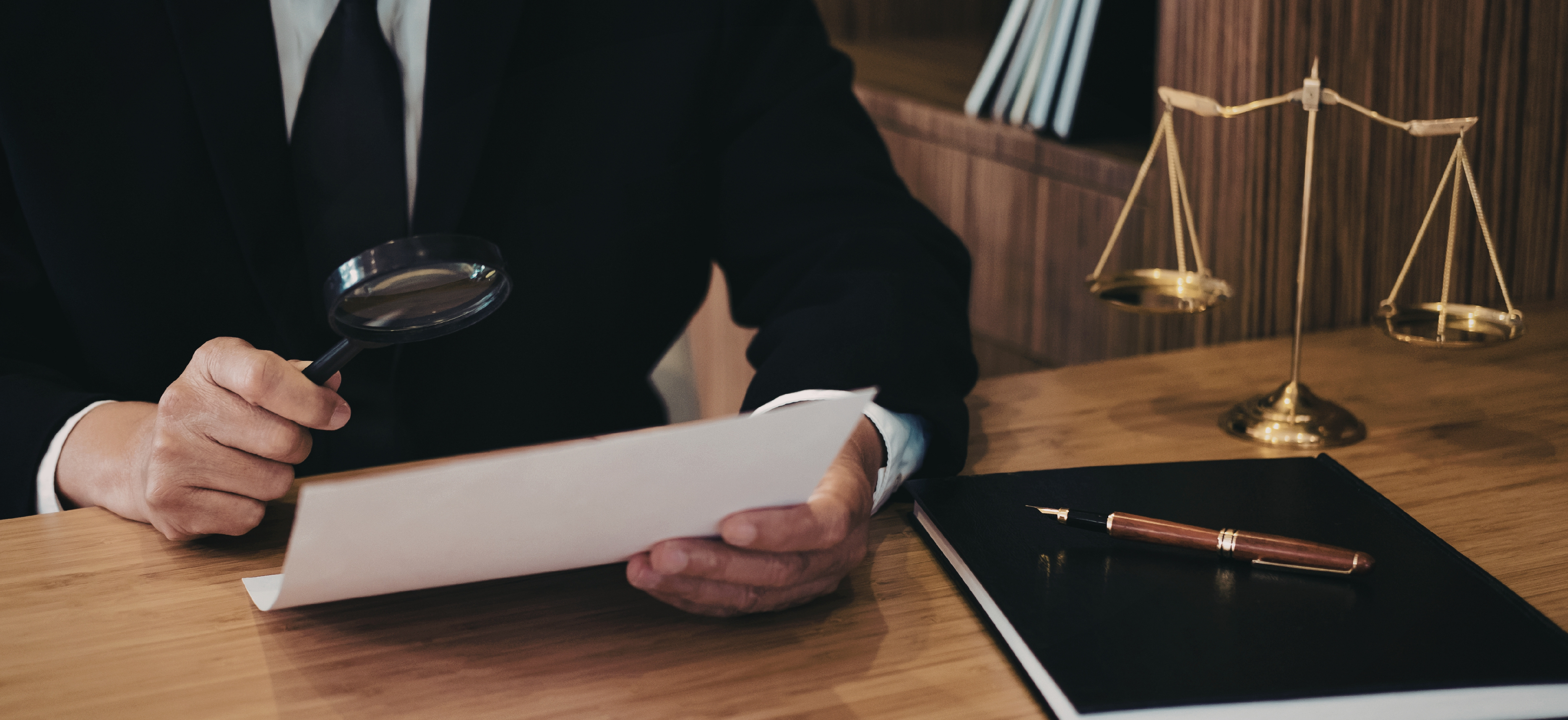 Attorney reviewing documents with a magnifying glass at a desk, representing law firm tax compliance and financial review