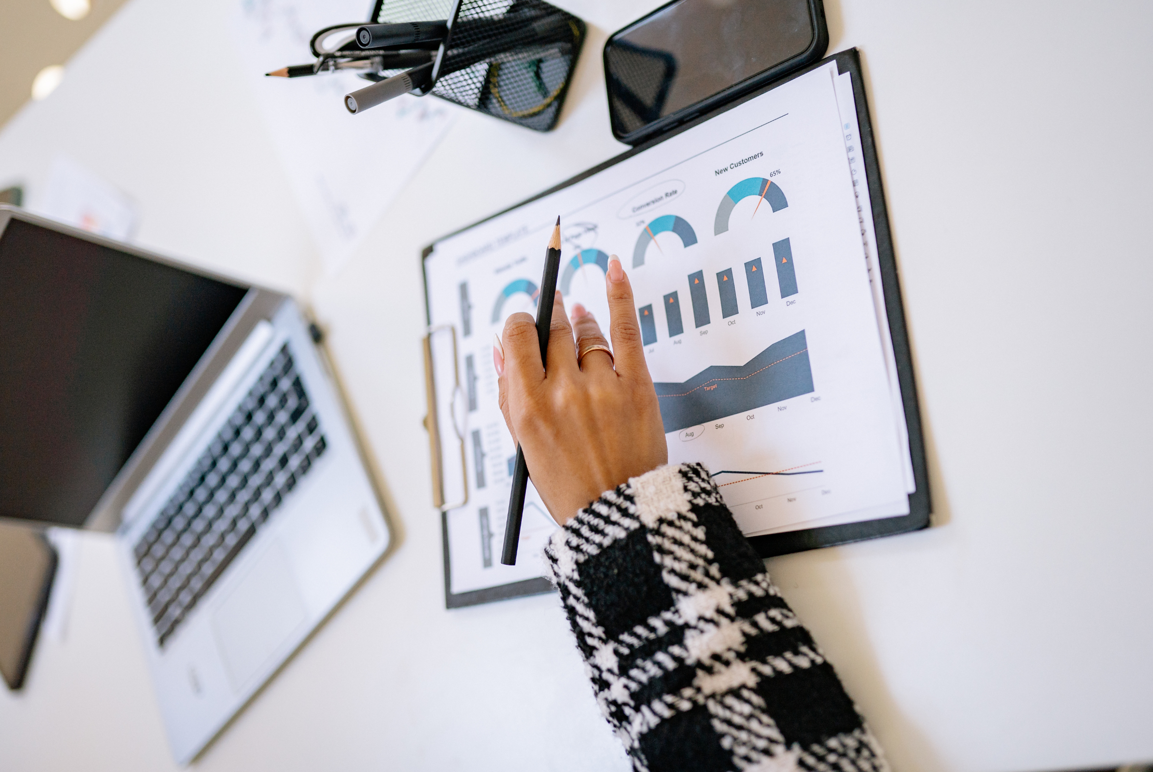 Person reviewing a KPI dashboard on a clipboard beside a laptop, analyzing law firm financial performance and forecasting.