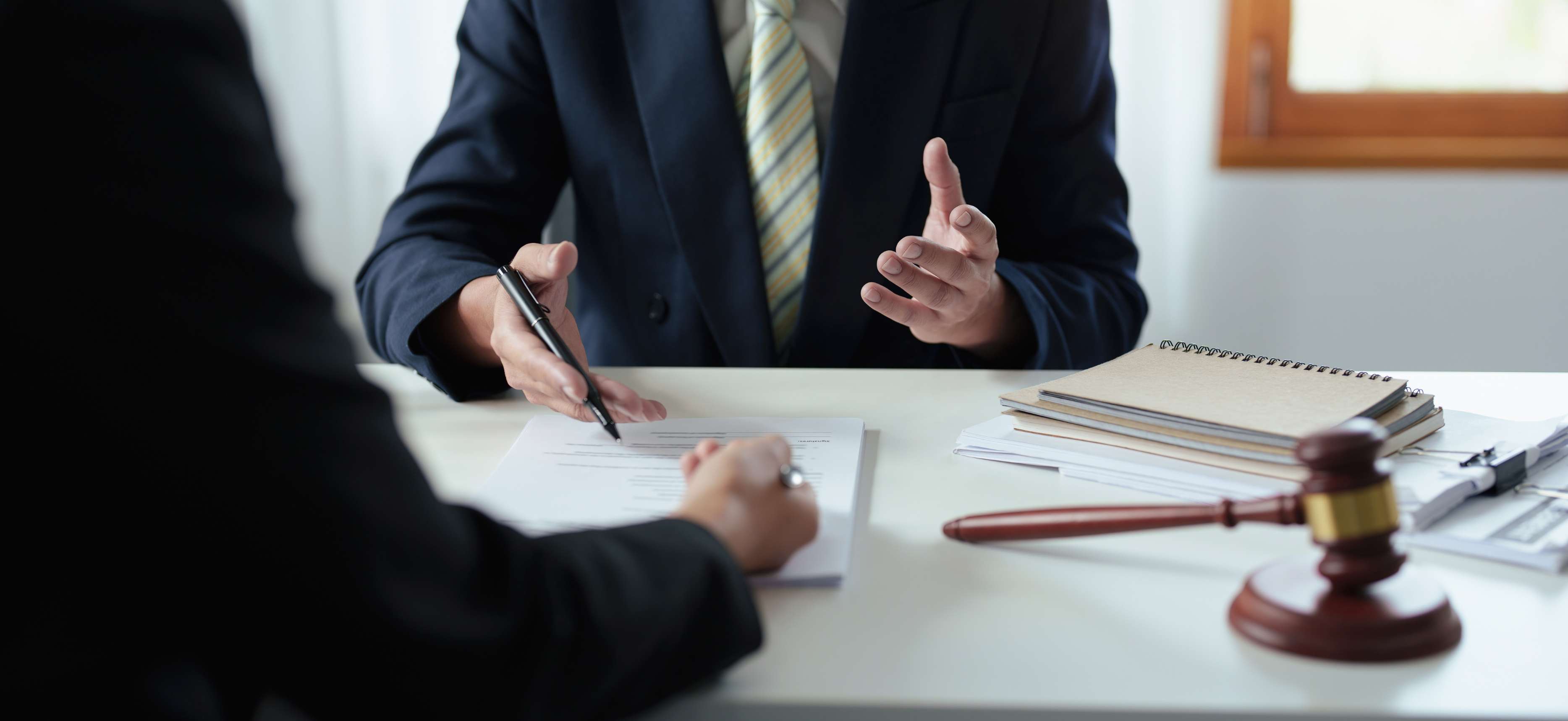 Attorney meeting with a law firm partner at a desk with legal documents and gavel, representing tax planning for law firms