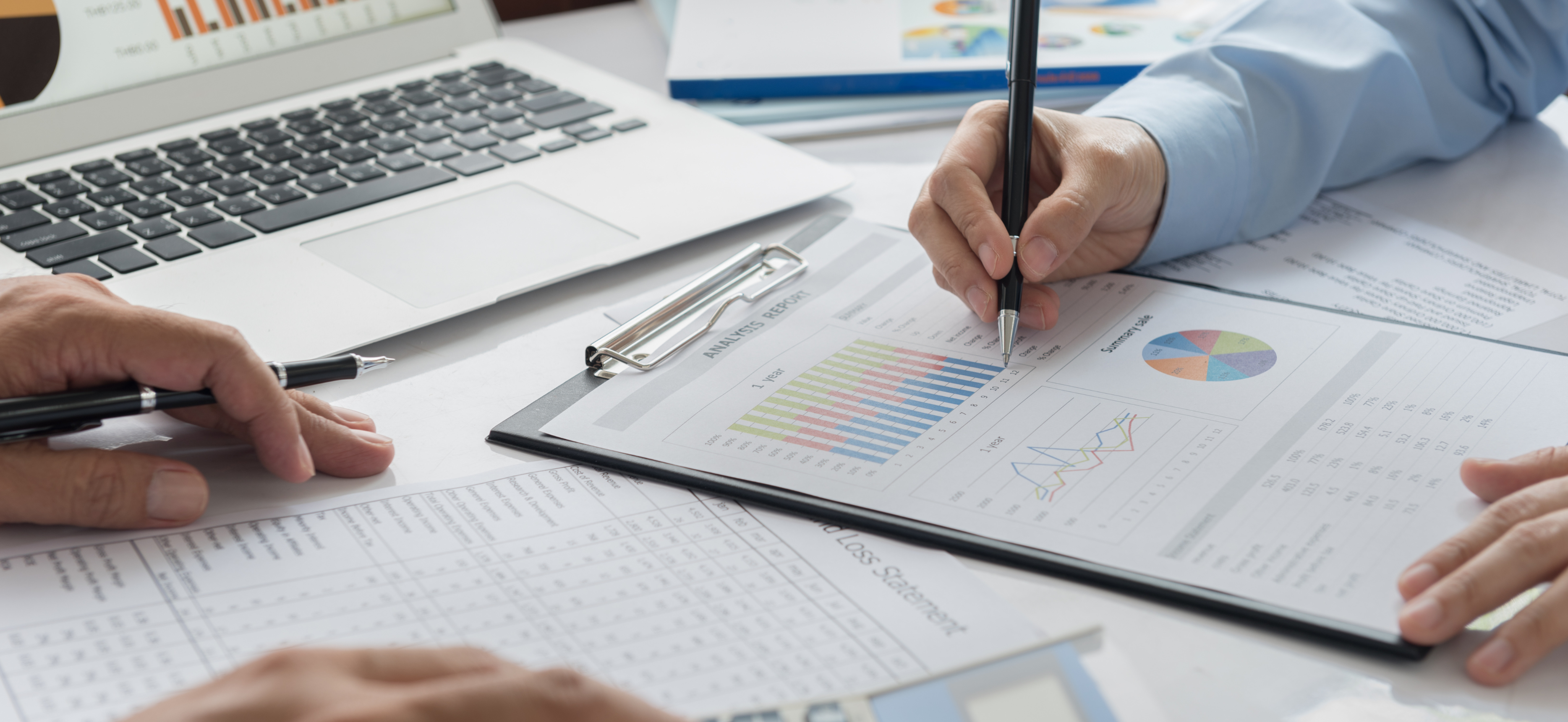 Law firm financial review with laptop and analytics report on clipboard, highlighting budgeting, forecasting, and profitability analysis.