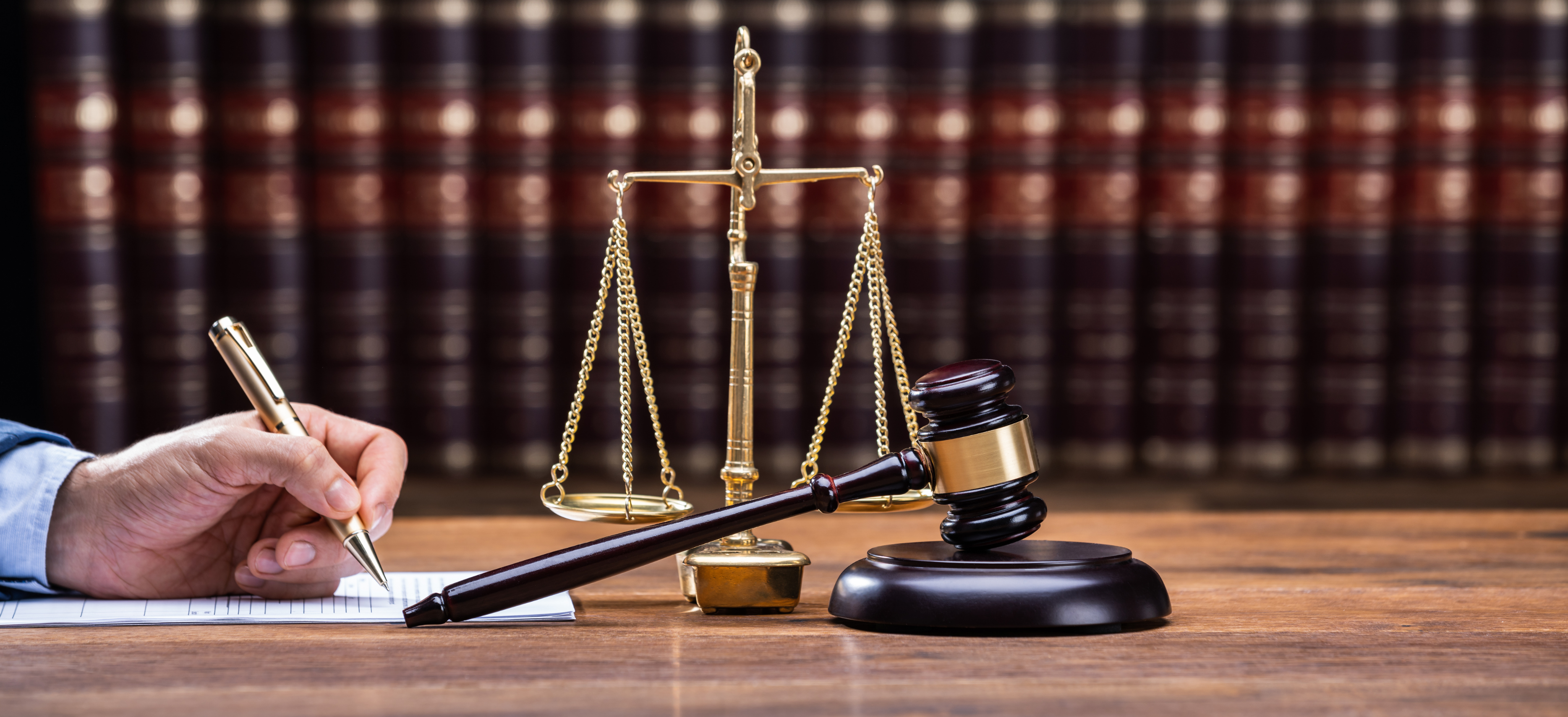 Lawyer signing tax documents in a law office with a gavel and scales, representing financial and tax oversight