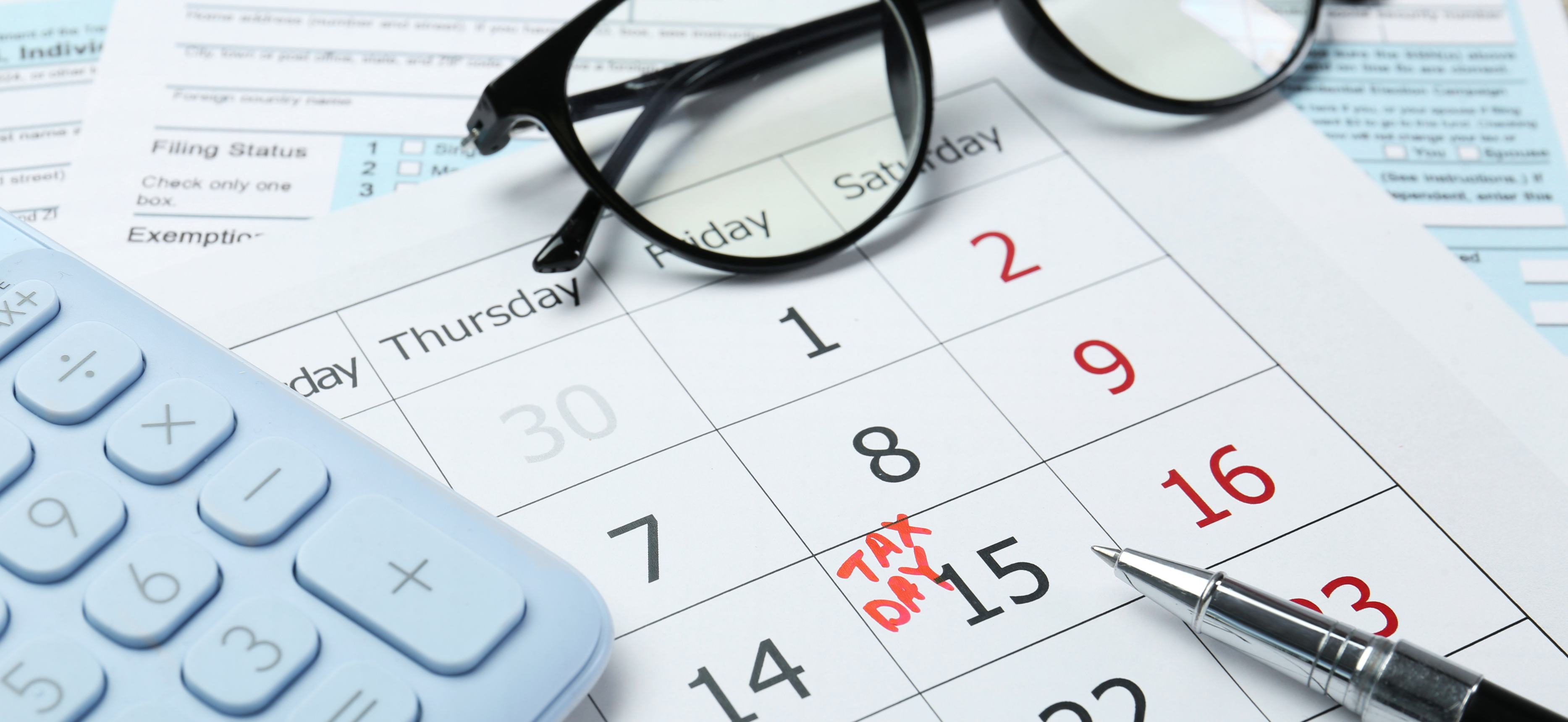 Tax deadline calendar with calculator, glasses, and tax forms, representing tax planning for law firm owners