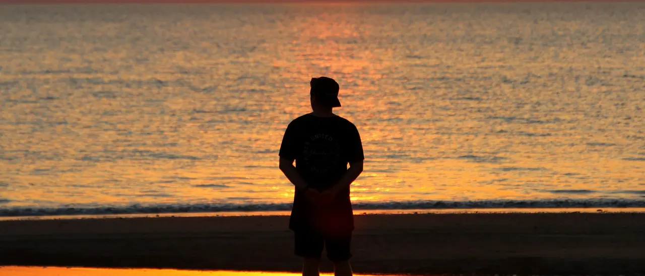 Late afternoon light over the water, with one person watching the sun go down.
