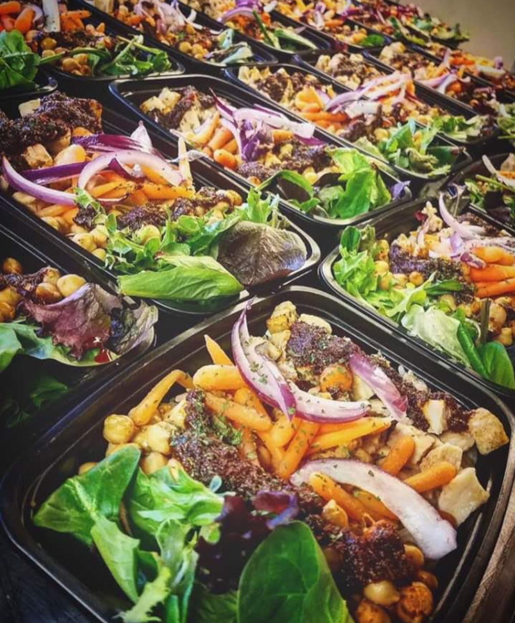 Rows of colorful prepared meal trays from the founder’s kitchen