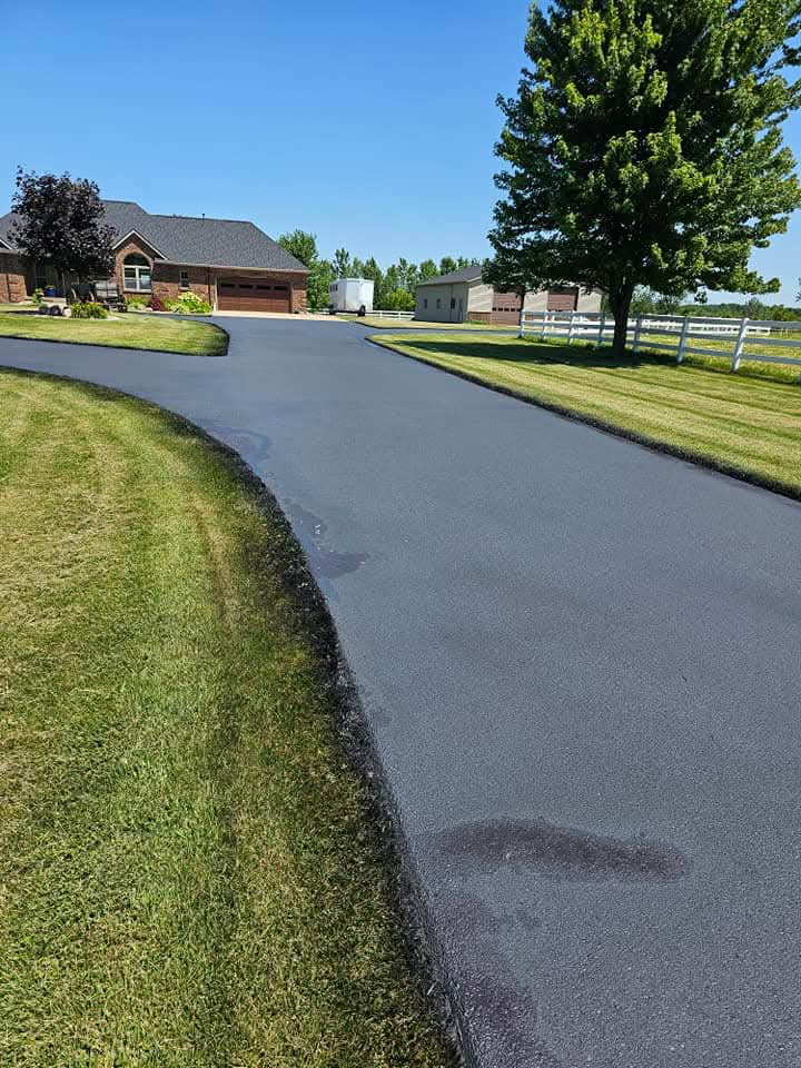 Professional asphalt sealcoating application on a residential driveway